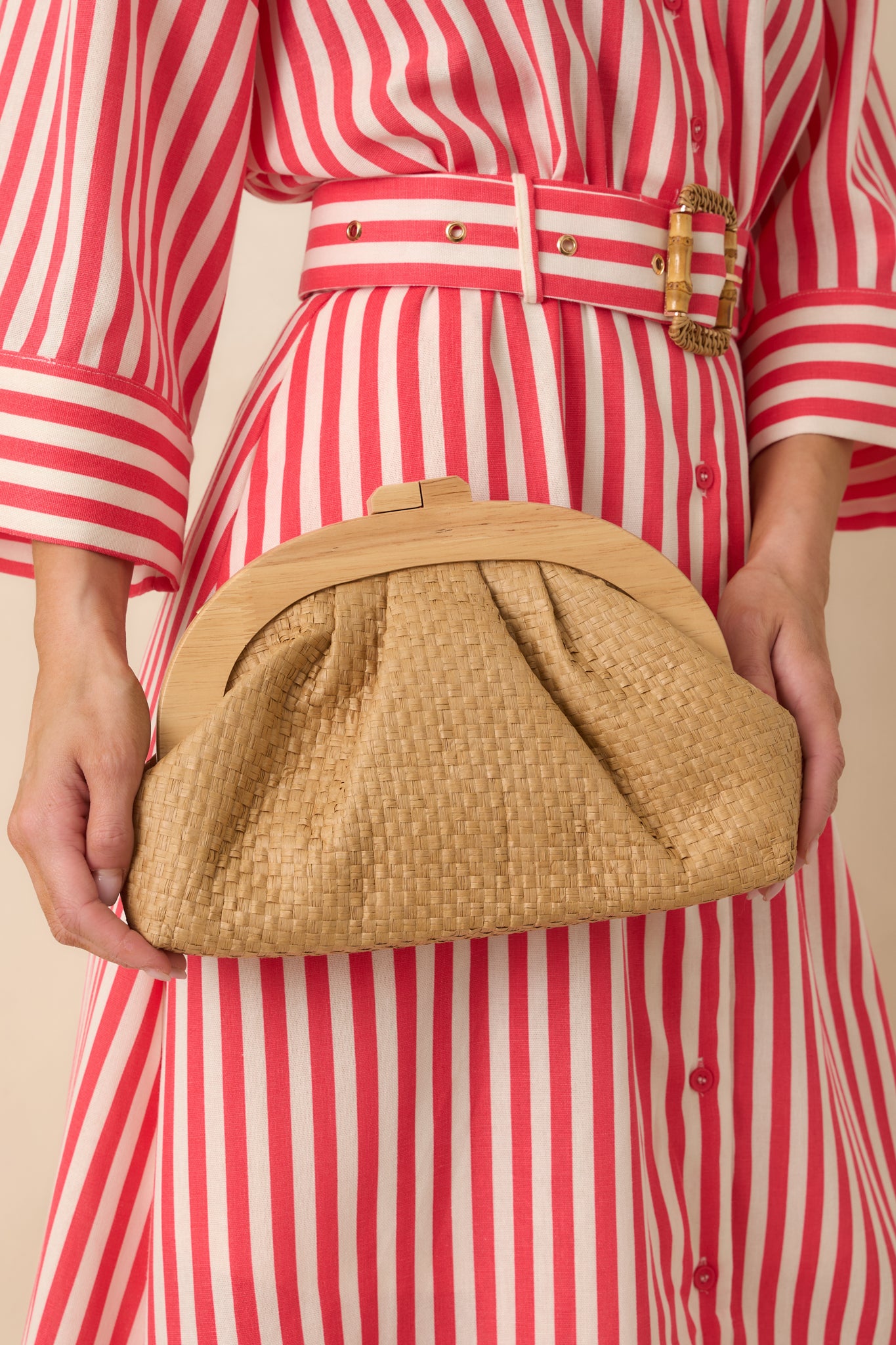 Detailed close-up of the tan clutch focusing on the woven texture, rounded wooden frame, and magnetic clasp.