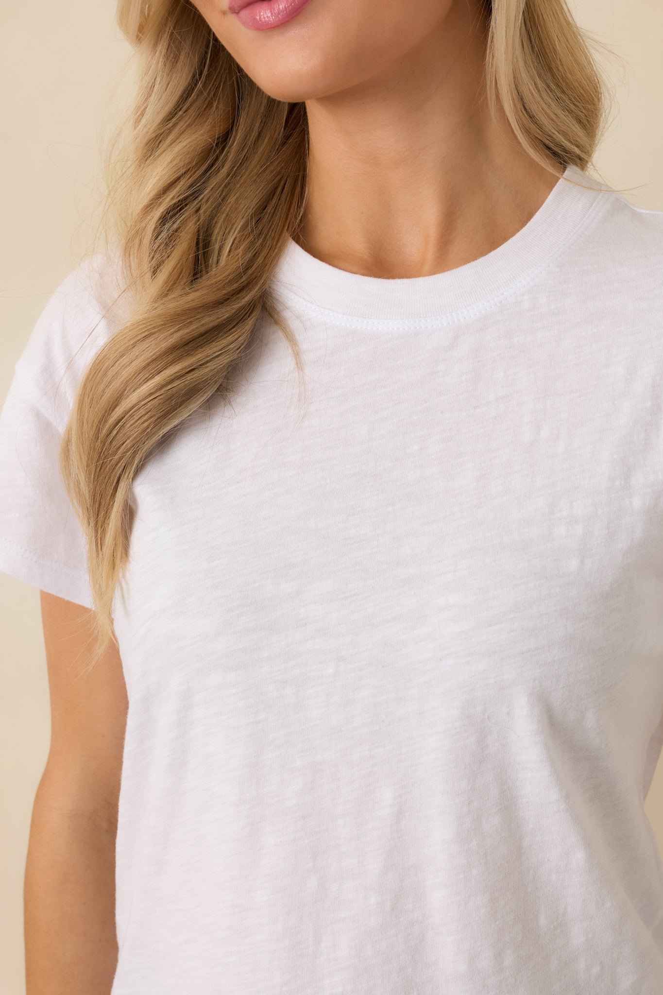 Close-up of white tee showing brushed slub jersey texture, crew neckline, and short sleeves.