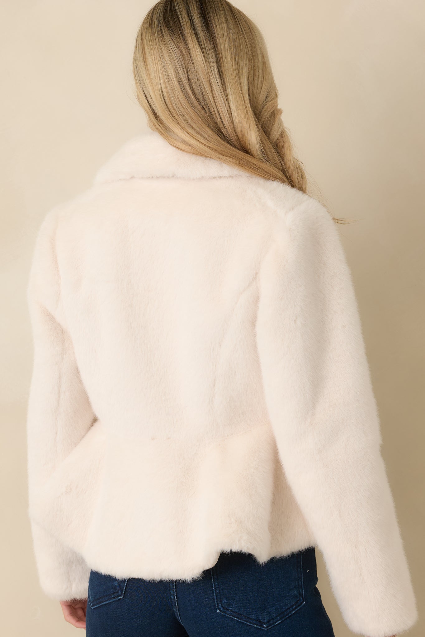 Rear view of the ivory faux fur coat displaying the clean back panel, long sleeves, and tailored fit through the body.