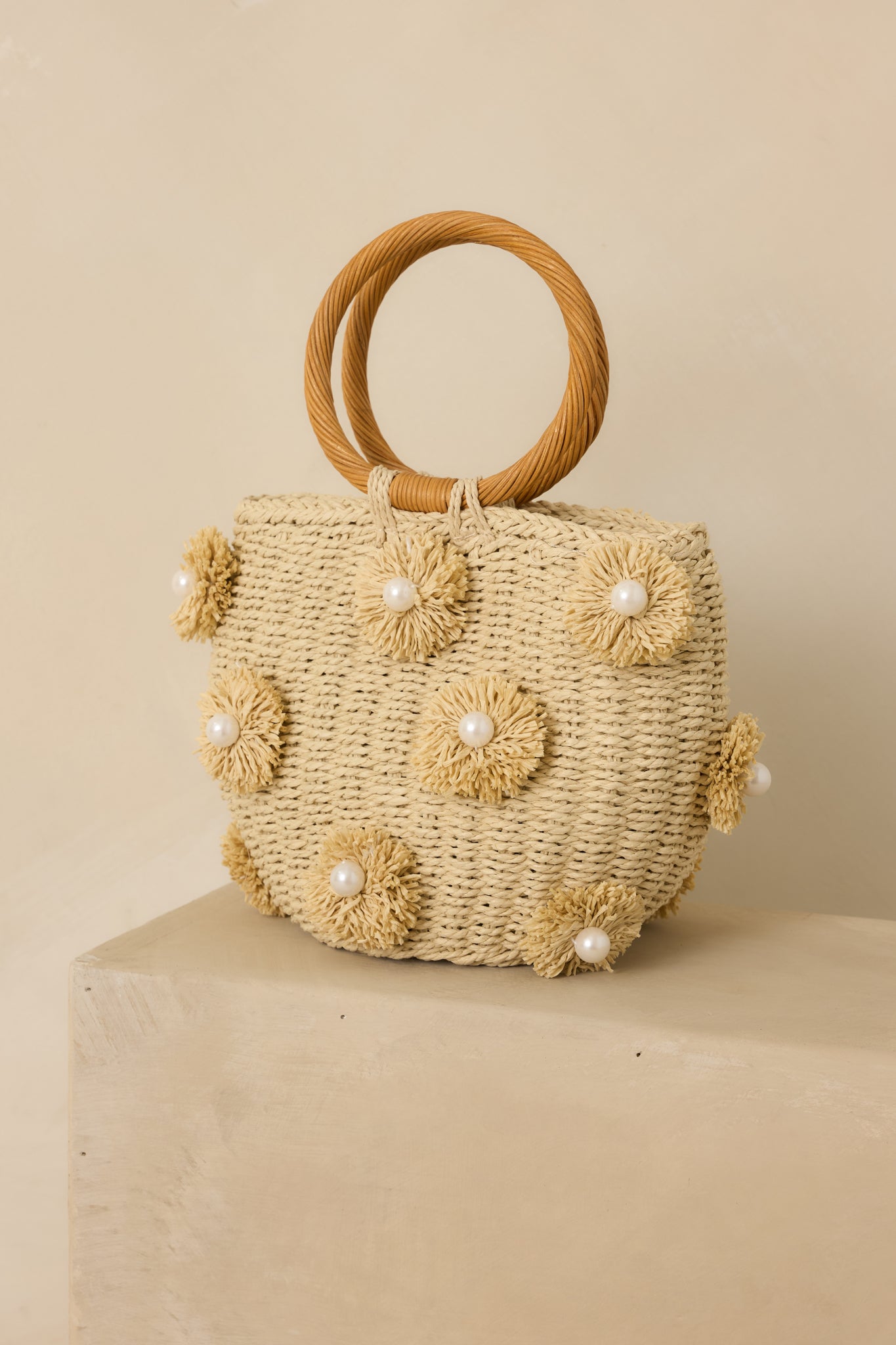 Cropped front view emphasizing the pearl detailing and woven texture of the natural handbag.