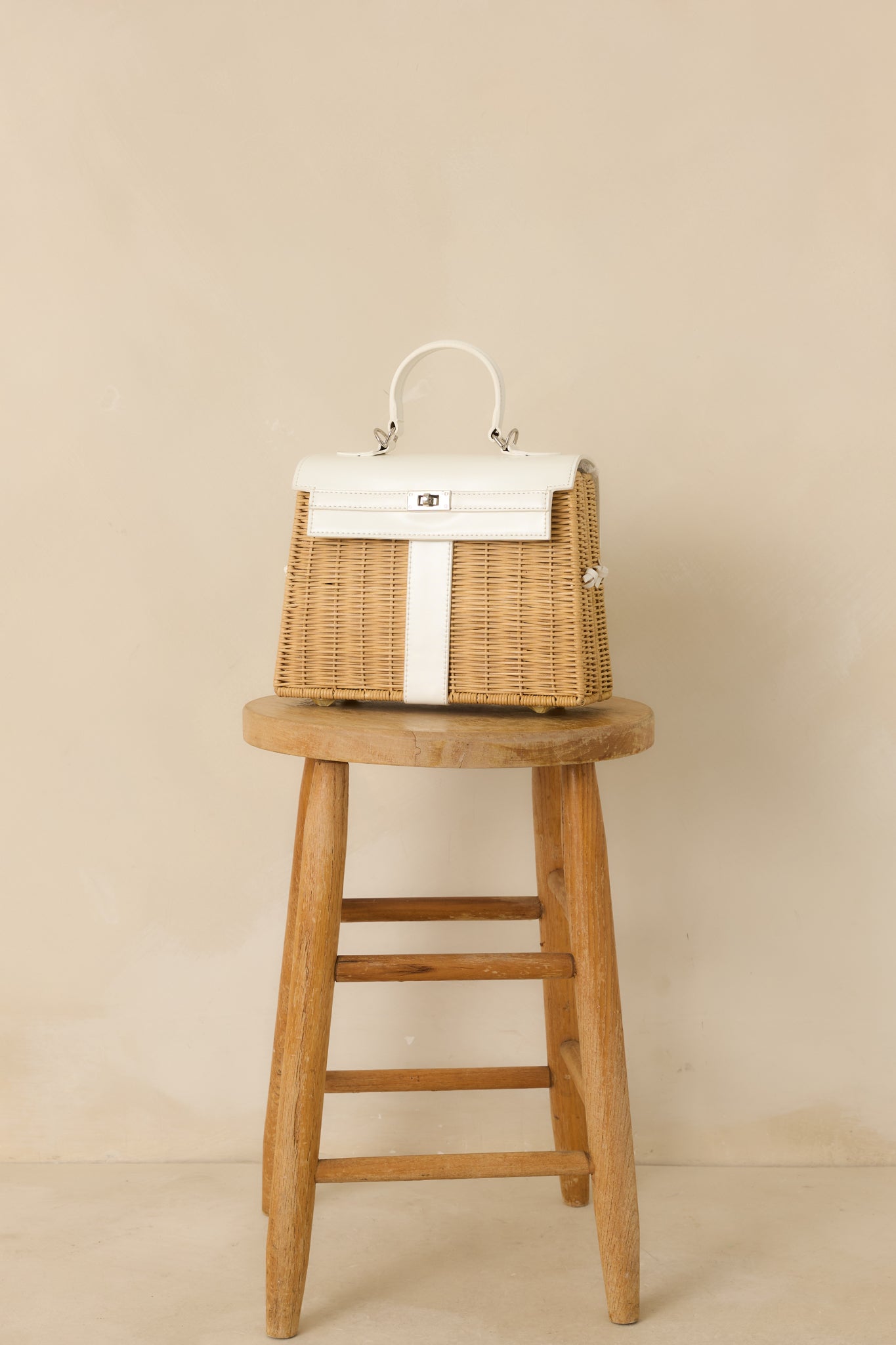 Angled full view of the white handbag highlighting the pop-open silhouette and fabric-connected side panels.