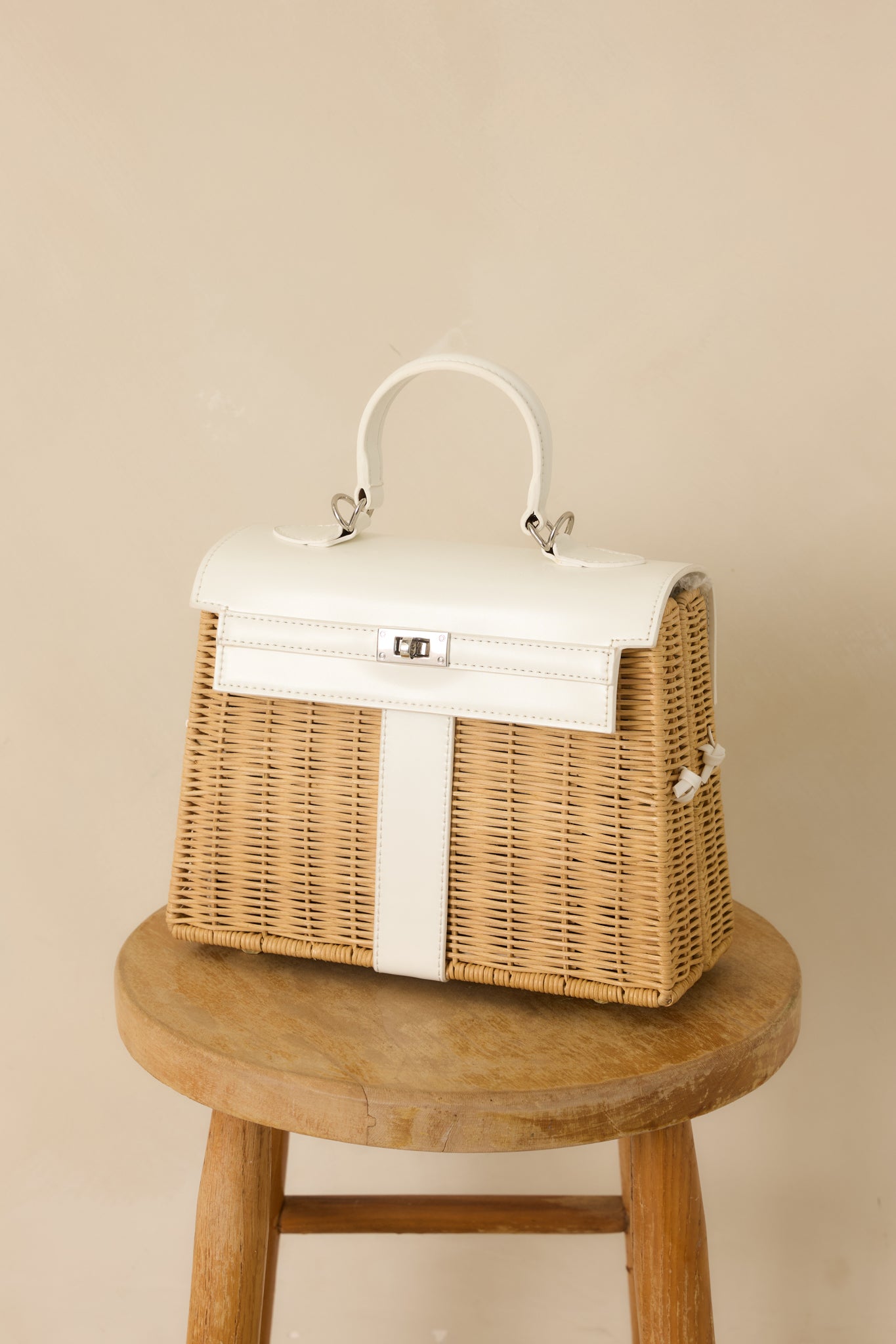 Close cropped angle showing the smooth faux leather trim and structured pop-open design of the white handbag.