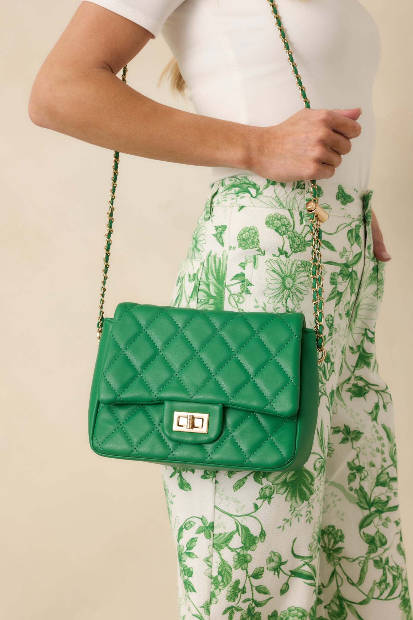 Cropped front view of the green quilted handbag emphasizing the flap design and polished gold-tone hardware.