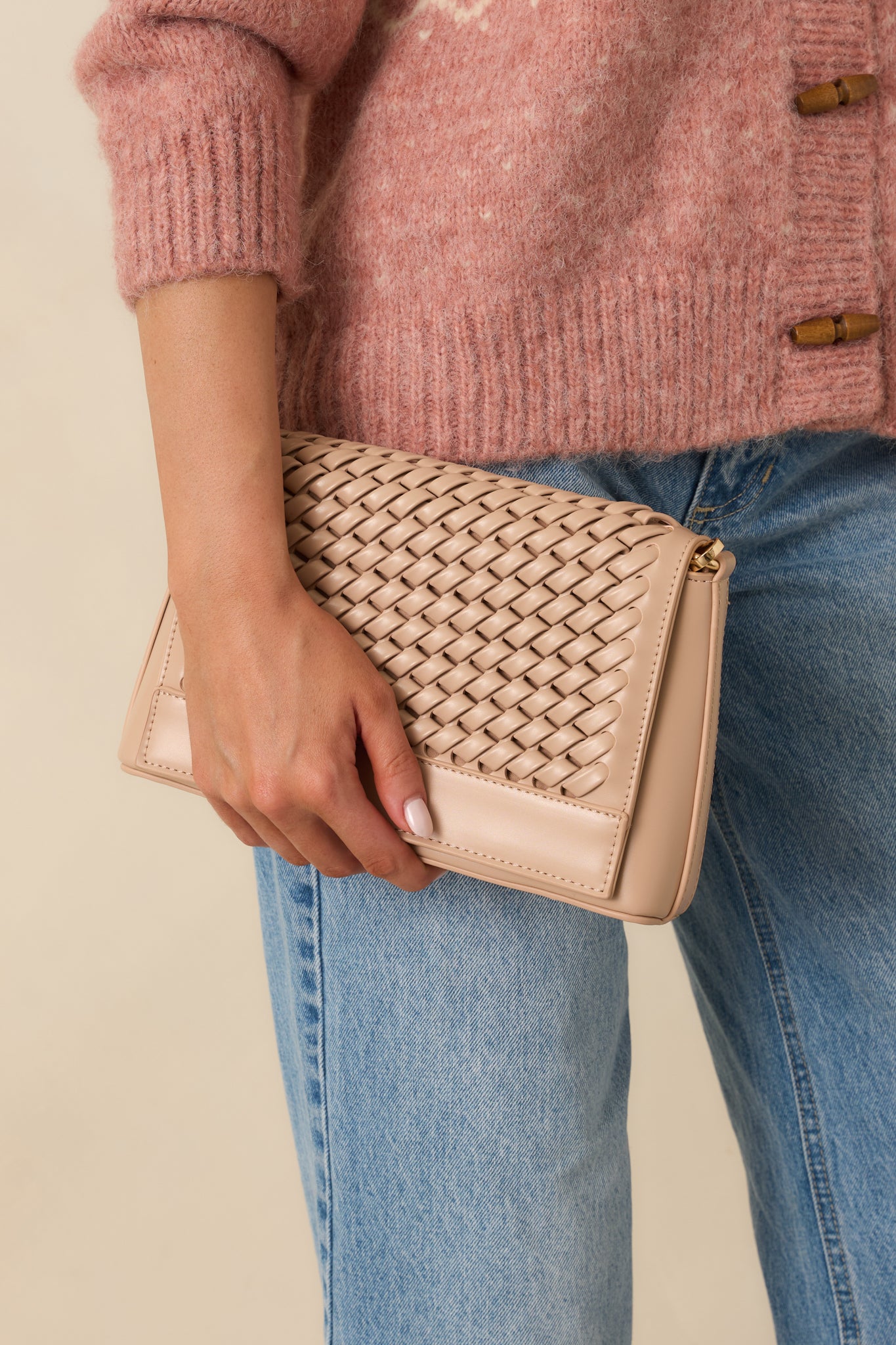 Close view of the woven faux leather texture and magnetic flap closure on the beige handbag.
