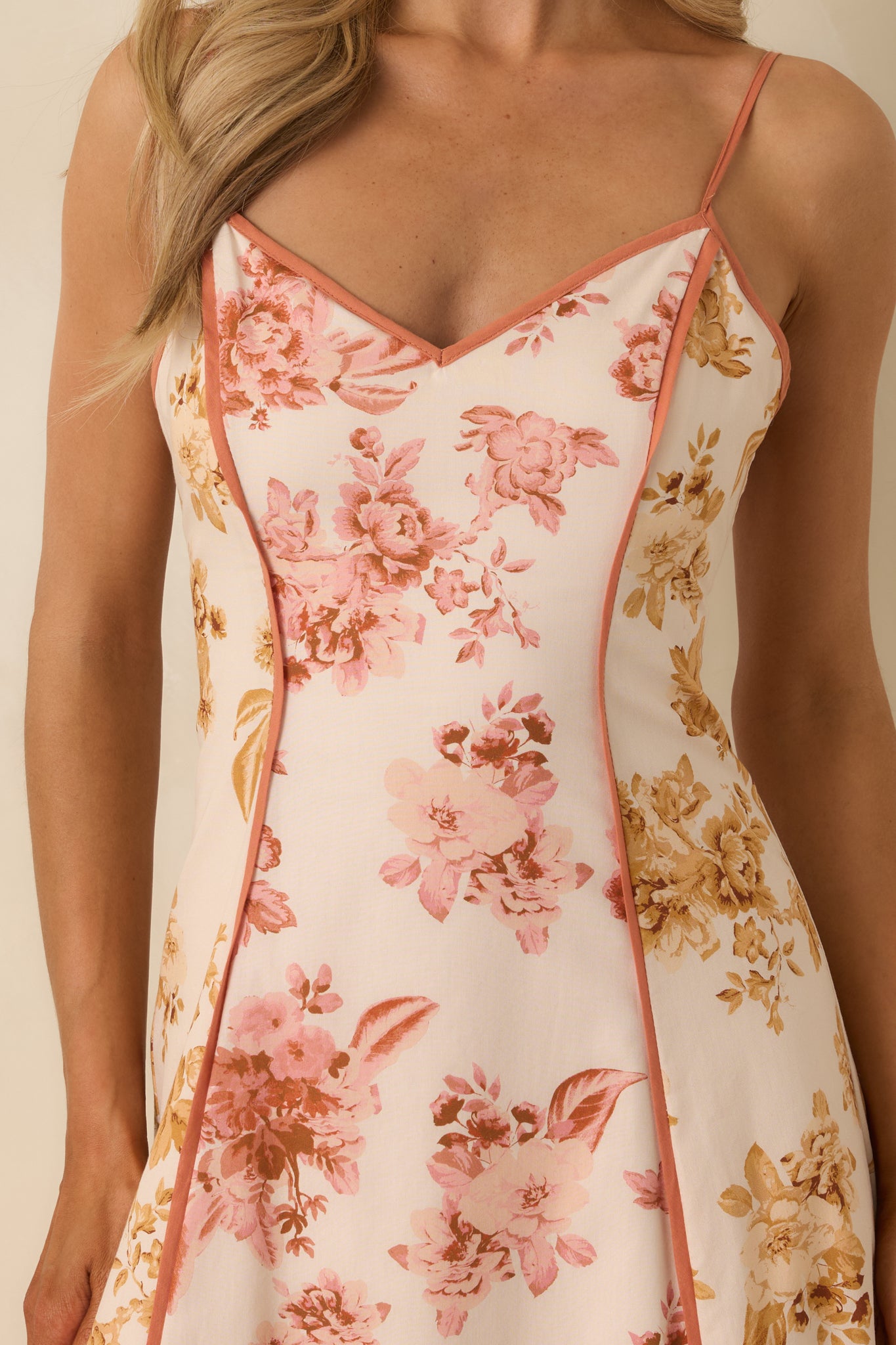 Close-up of maxi dress showing floral print panels, clay trim detailing, and adjustable spaghetti straps.