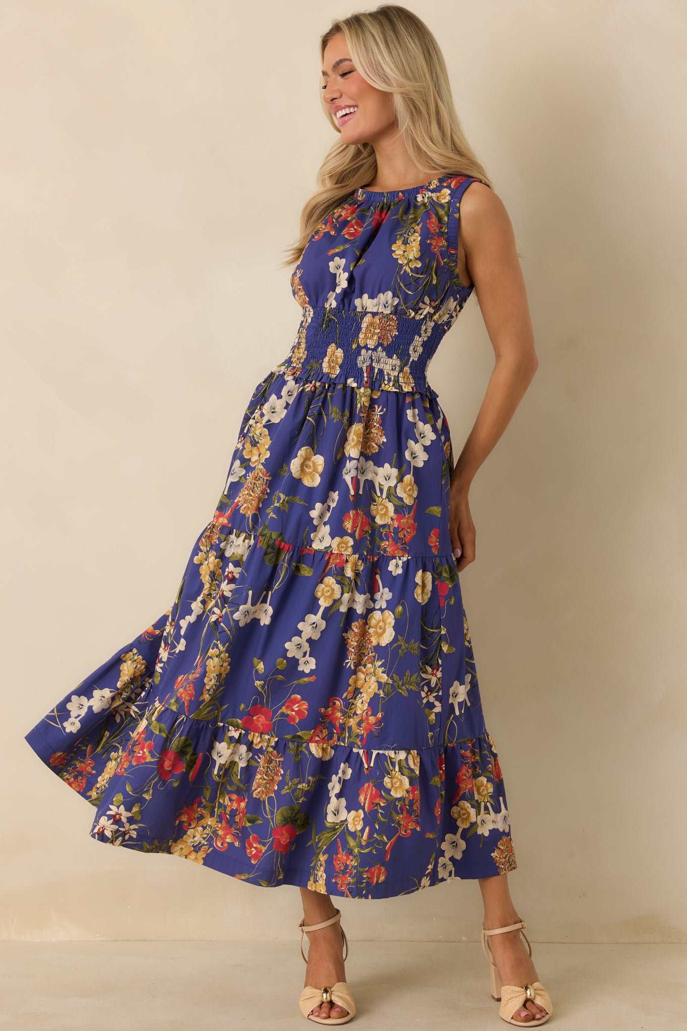 Sleeveless cobalt blue maxi dress with gathered neckline, smocked waist, and multicolor floral pattern with flowing tiers.