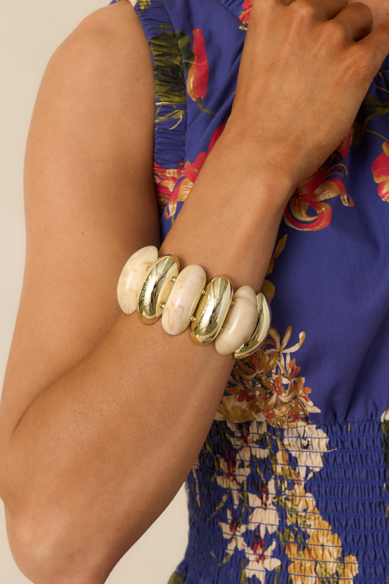 Statement bracelet with smooth beige beads and metallic gold accents, arranged on flexible stretch bands in a two-row silhouette.