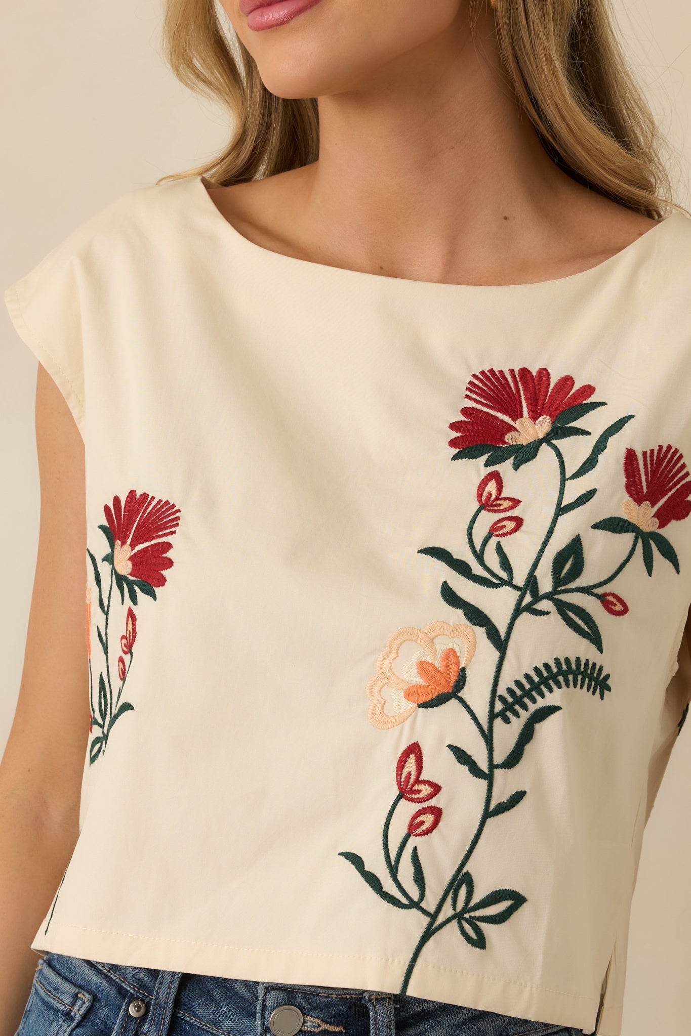 Detailed look at the embroidered floral pattern, cap sleeves, and lined construction on the natural-colored top.