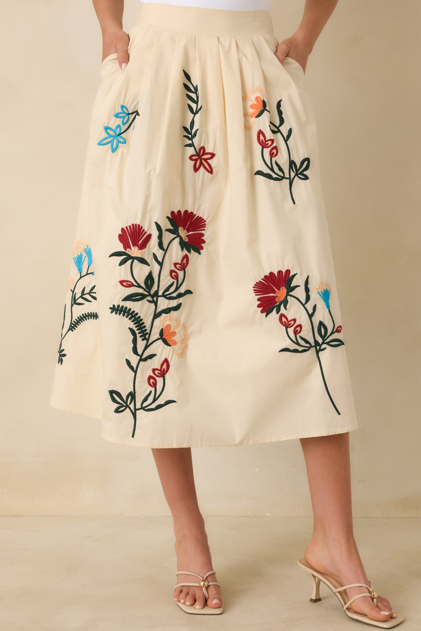 Closer view of the soft pleating and floral embroidery along the natural-colored fabric.