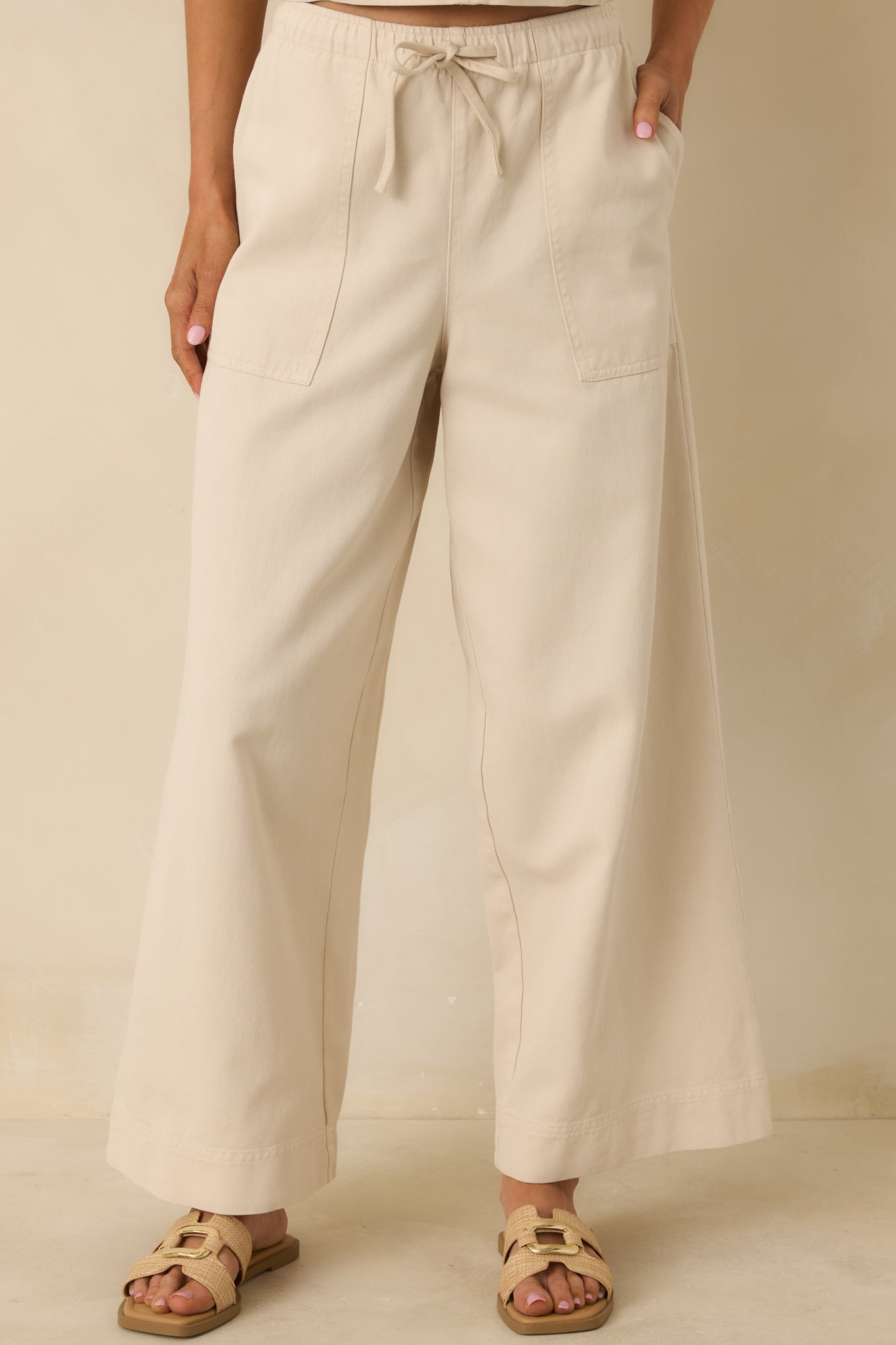 Beige wide-leg pants emphasizing the relaxed fit and fluid drape through the legs.