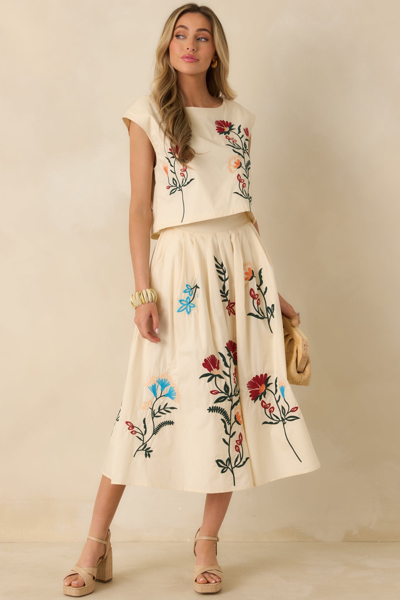 Front view of the natural top showing bateau neckline, subtle floral embroidery, and polished straight hem.