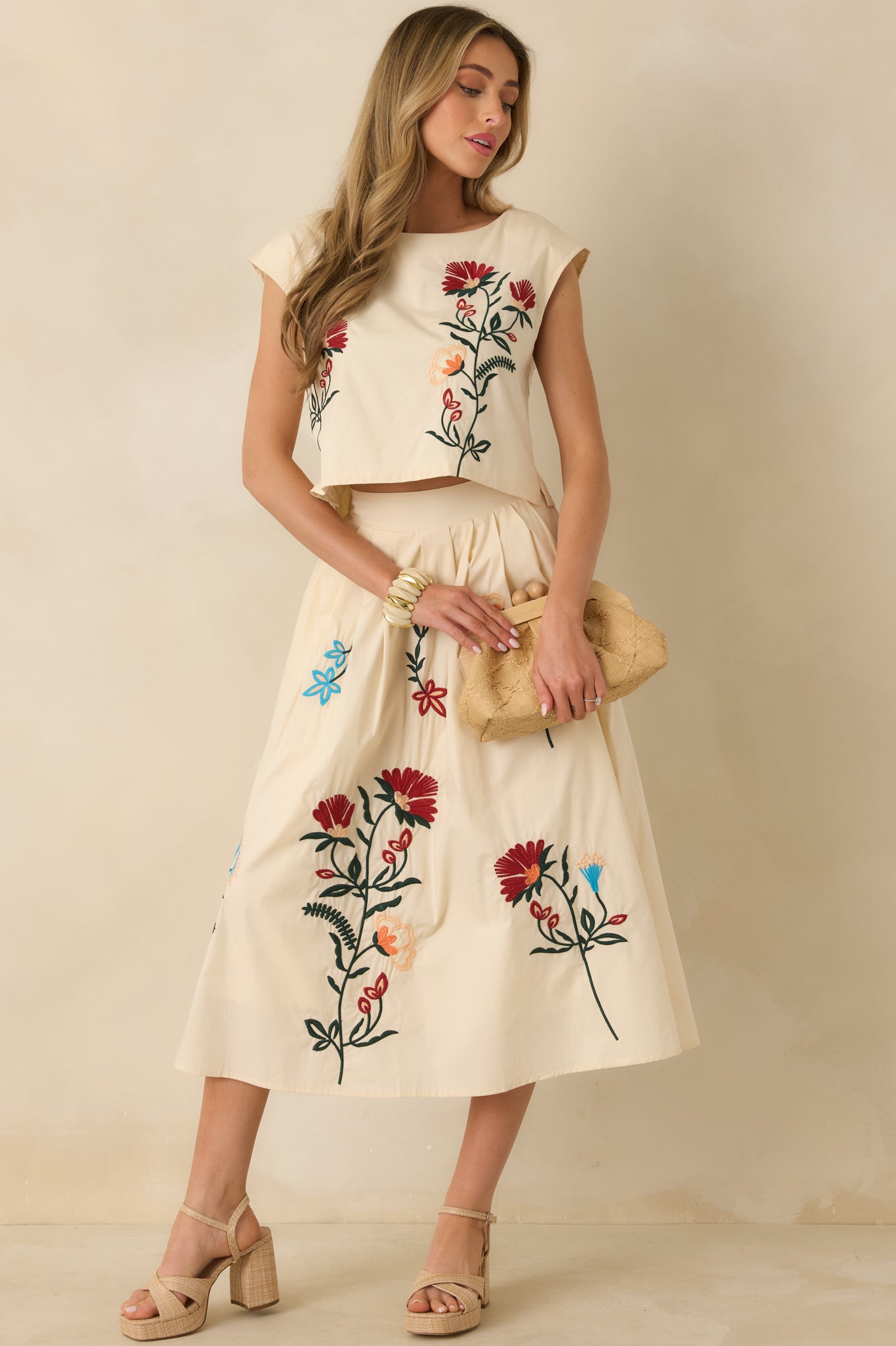 Cropped-length natural top featuring a straight hem, embroidered floral detailing, and feminine cap sleeves.