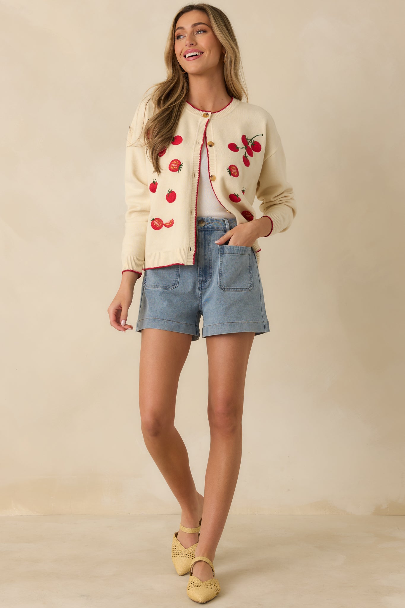 Knit ivory cardigan with functional button-front closure, ribbed detailing, and embroidered cherry tomato pattern.