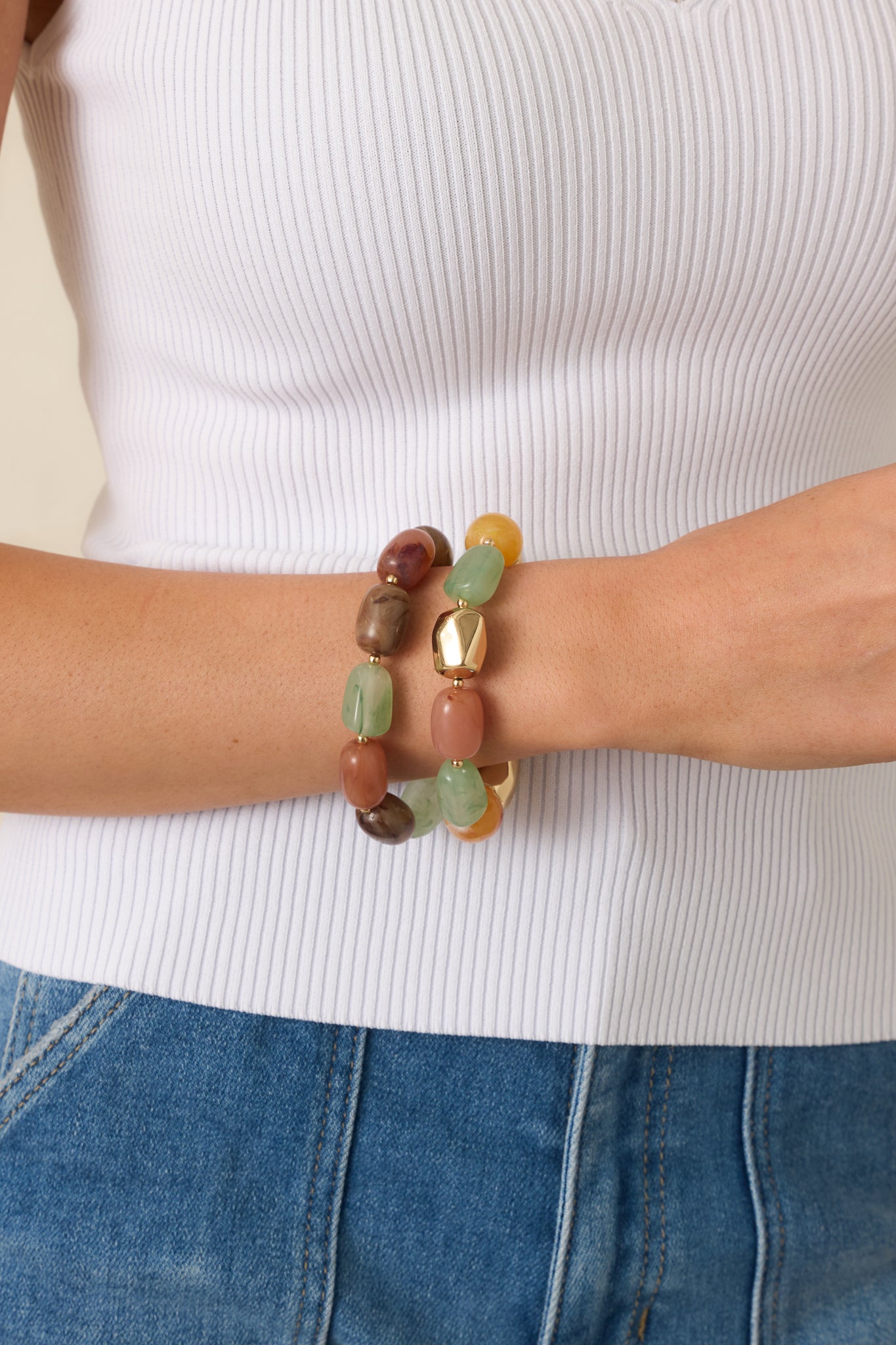 Close-up detail of the bracelet set highlighting smooth rounded beads and gold-tone metal accents.