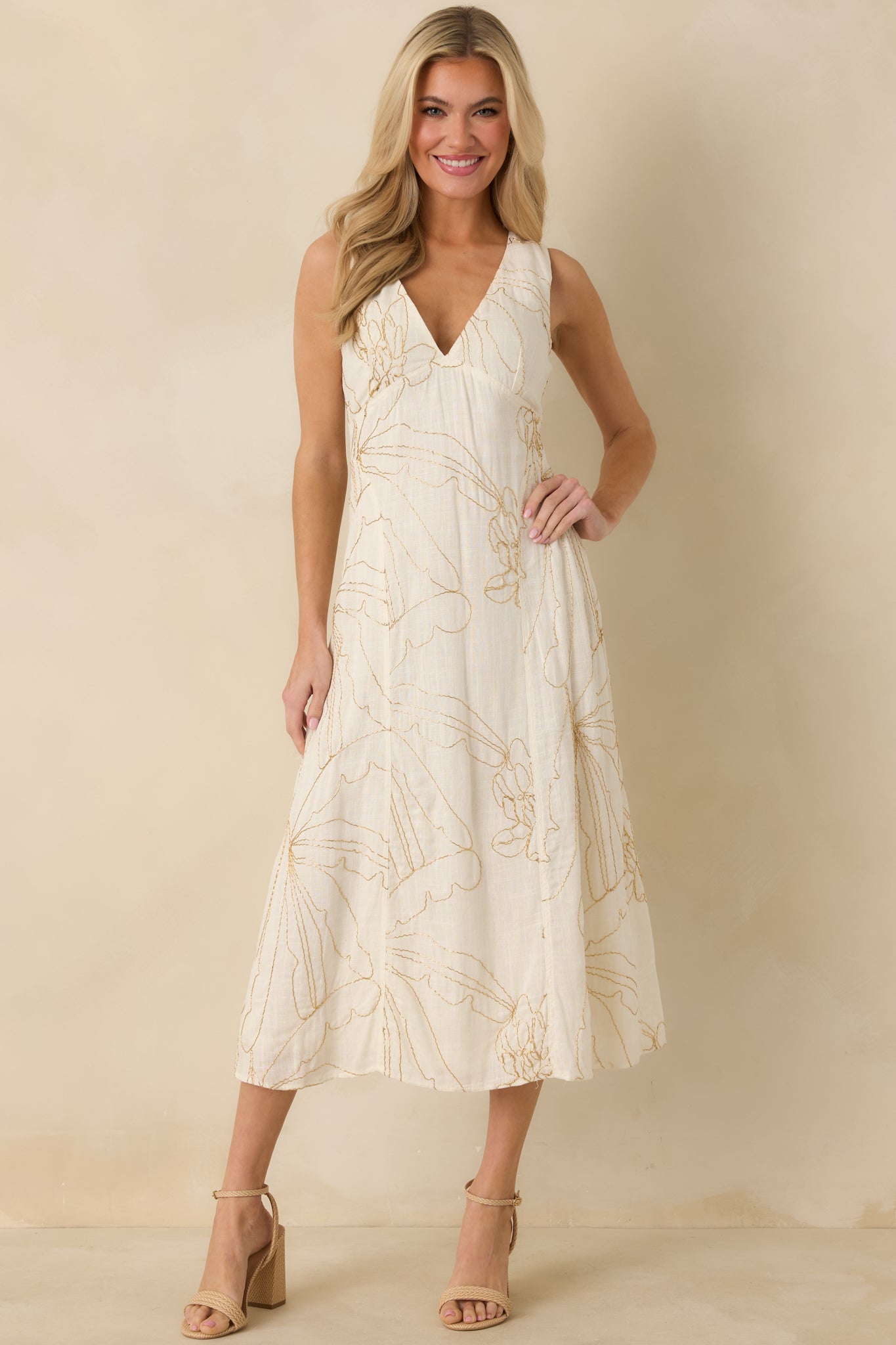 Midi-length ivory dress featuring intricate golden floral beadwork, a fitted bodice, and a soft, flowing skirt with a deep V-neckline.