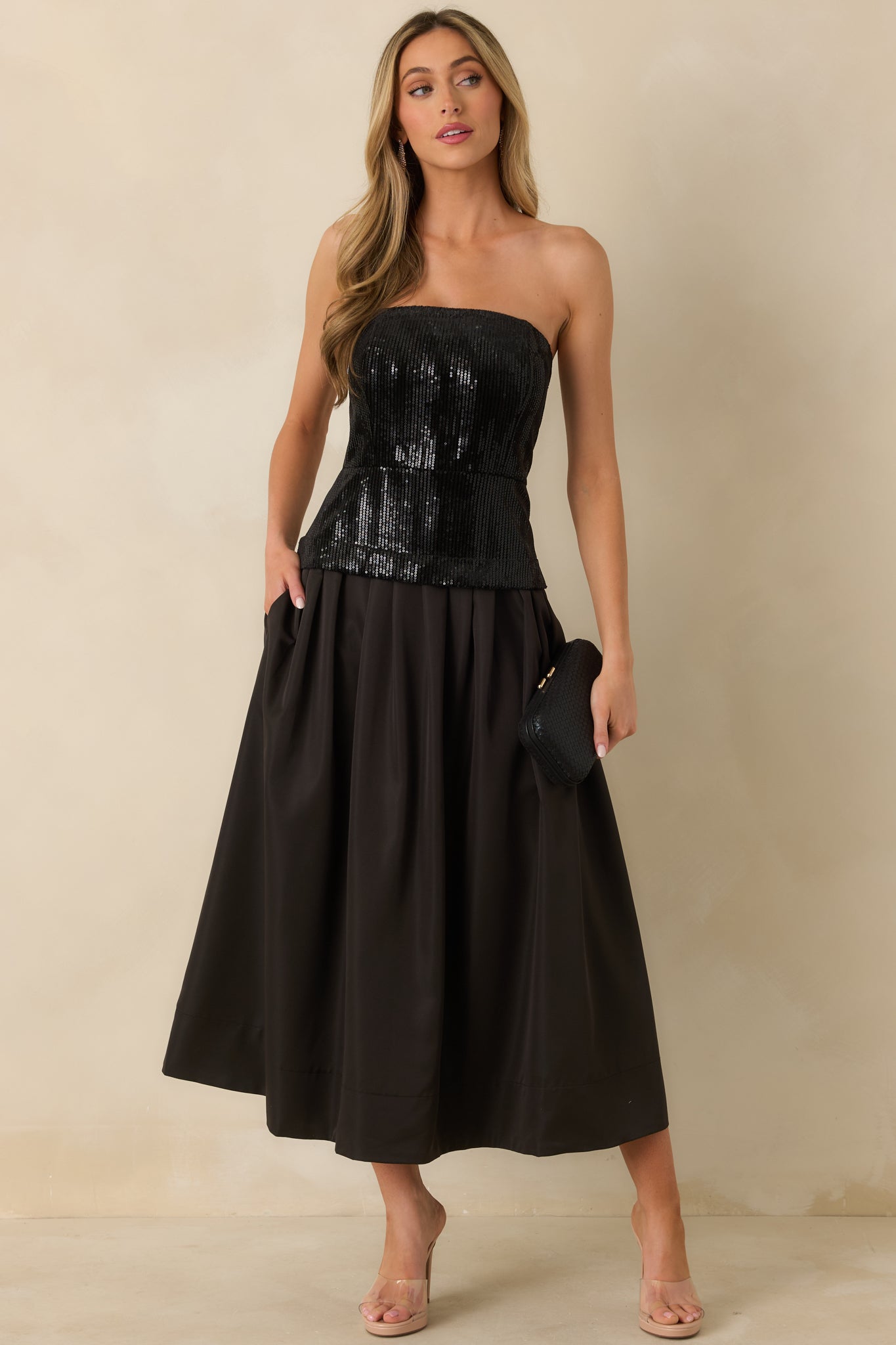 Strapless black midi dress featuring a sequined bodice with boning and a flowing pleated skirt for a flattering fit-and-flare shape.