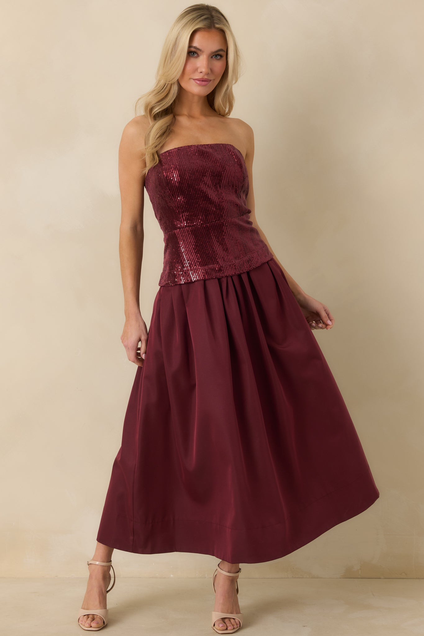 Strapless deep cherry red midi dress featuring a sequined bodice with boning and a flowing pleated skirt for a flattering fit-and-flare shape.