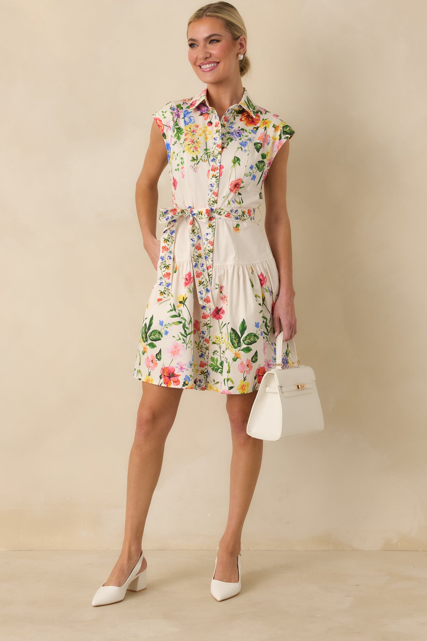 White floral mini dress designed with structured bodice, collared neckline, and flowing skirt.
