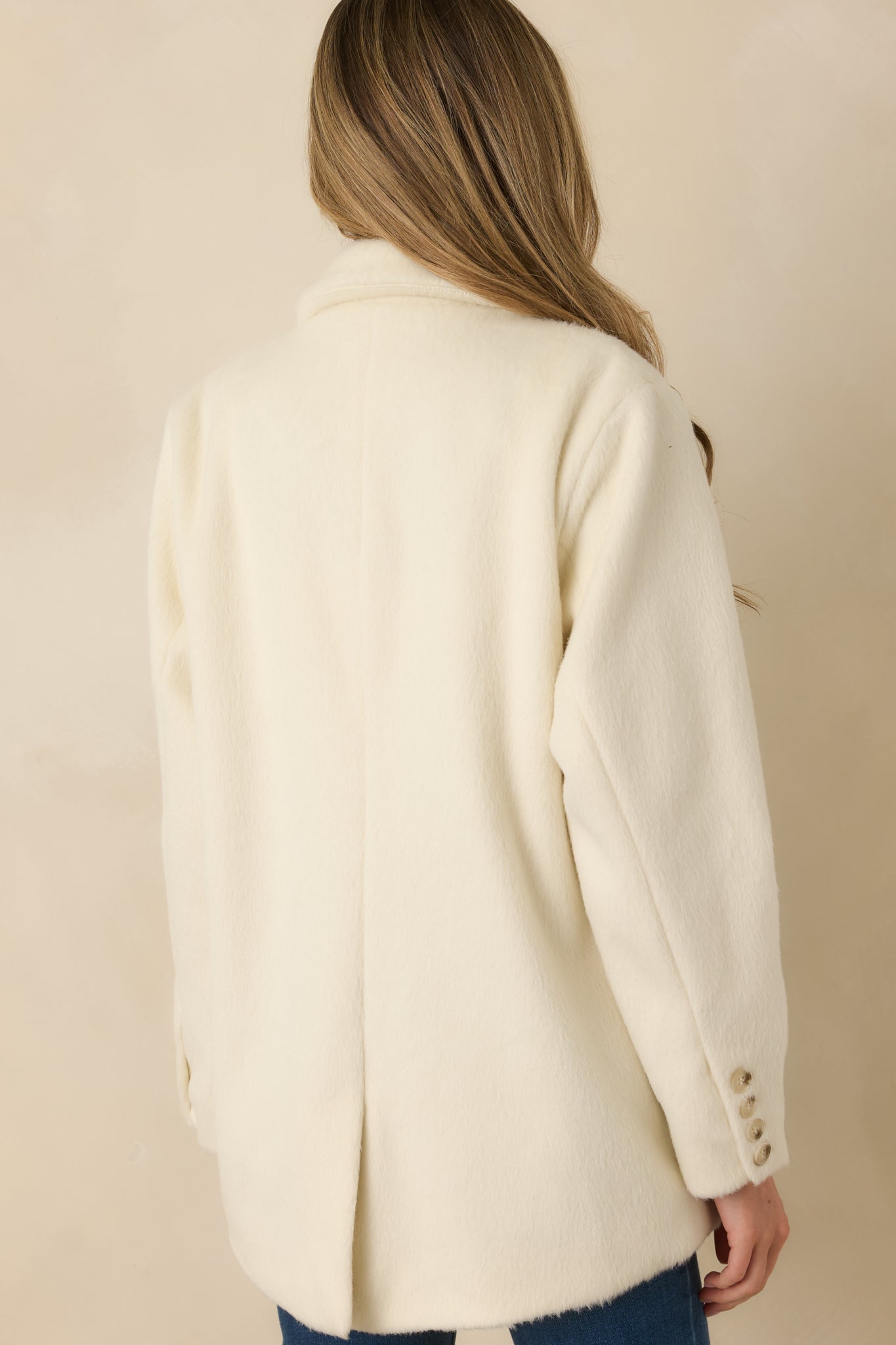 Rear view of ivory blazer showing smooth felted texture and structured shape.