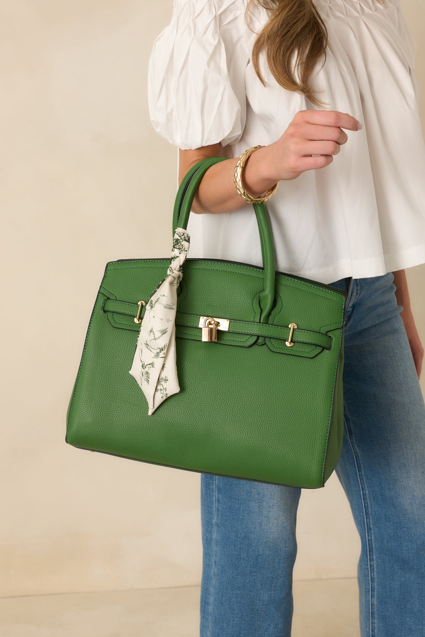 Cropped front view emphasizing handbag’s top handles, scarf detail, and smooth green exterior.