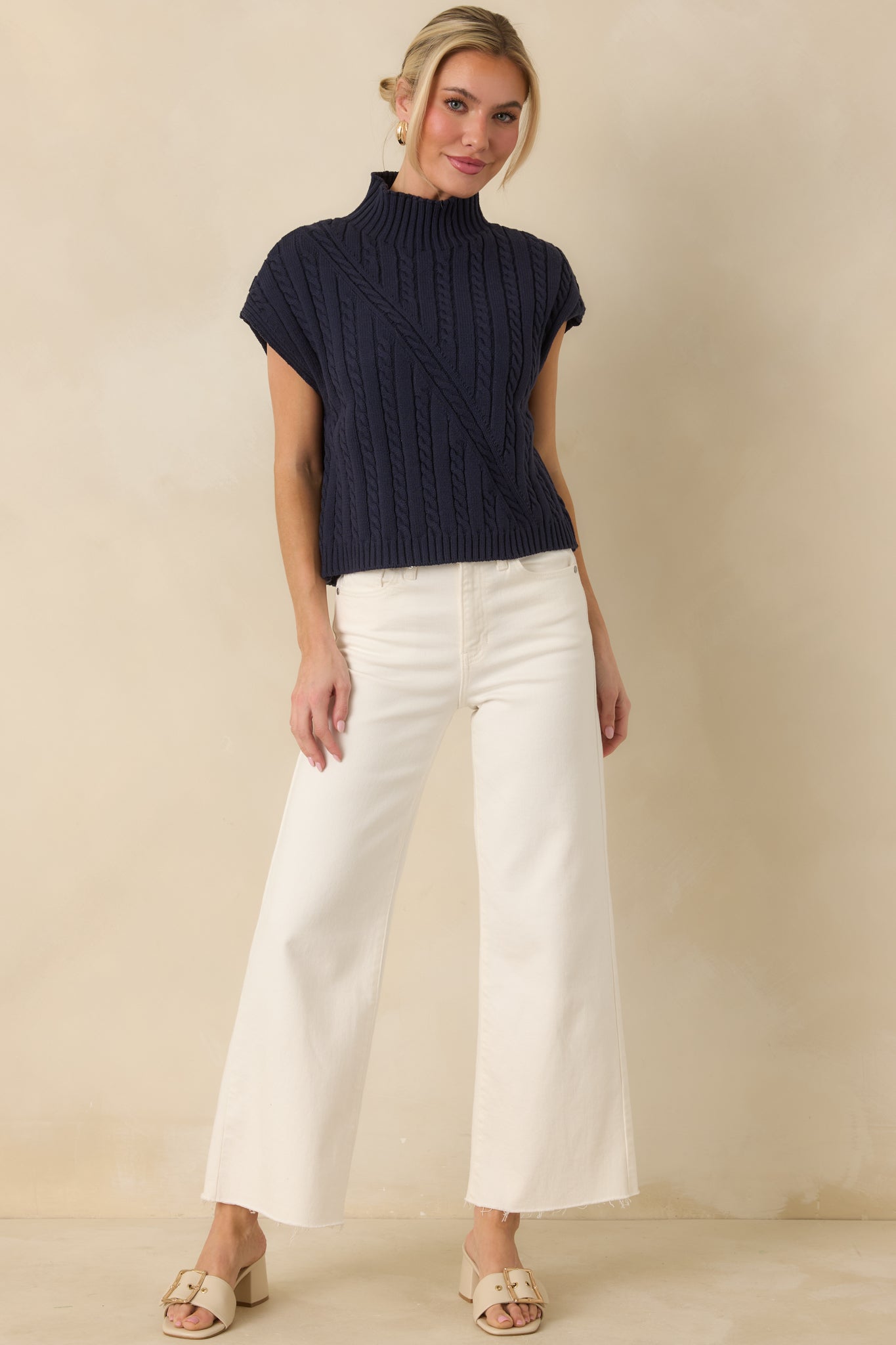 Sleeveless navy cable knit top highlighting the structured knit design and crisp ribbed neckline finish.