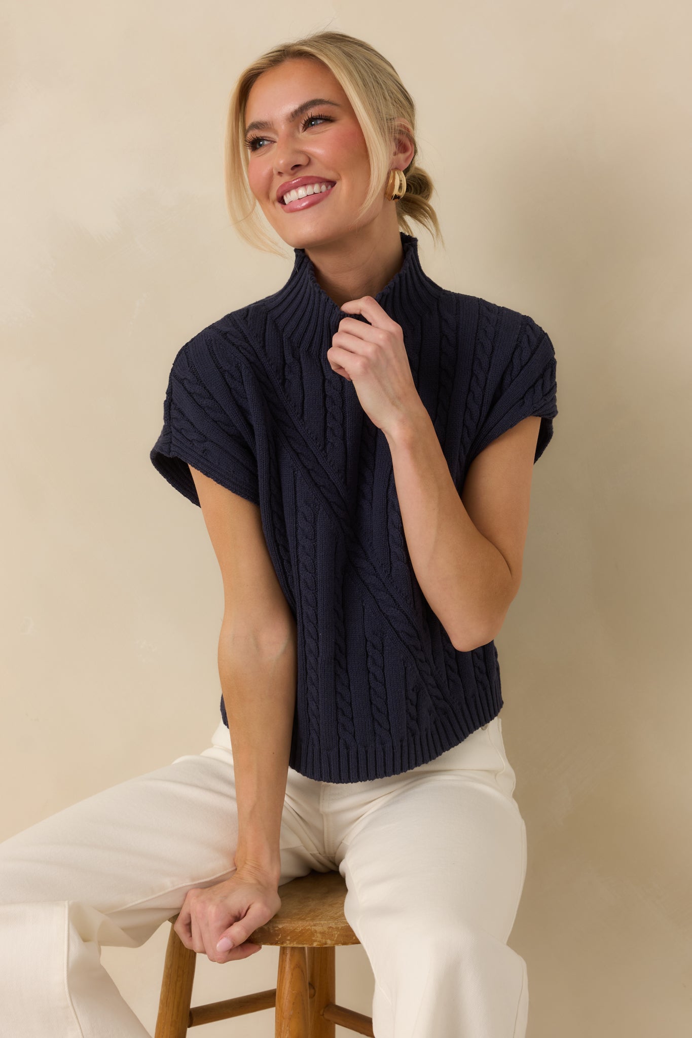 Navy sleeveless sweater with a mock neckline, featuring a structured cable-knit pattern and a relaxed, easy-layering silhouette.
