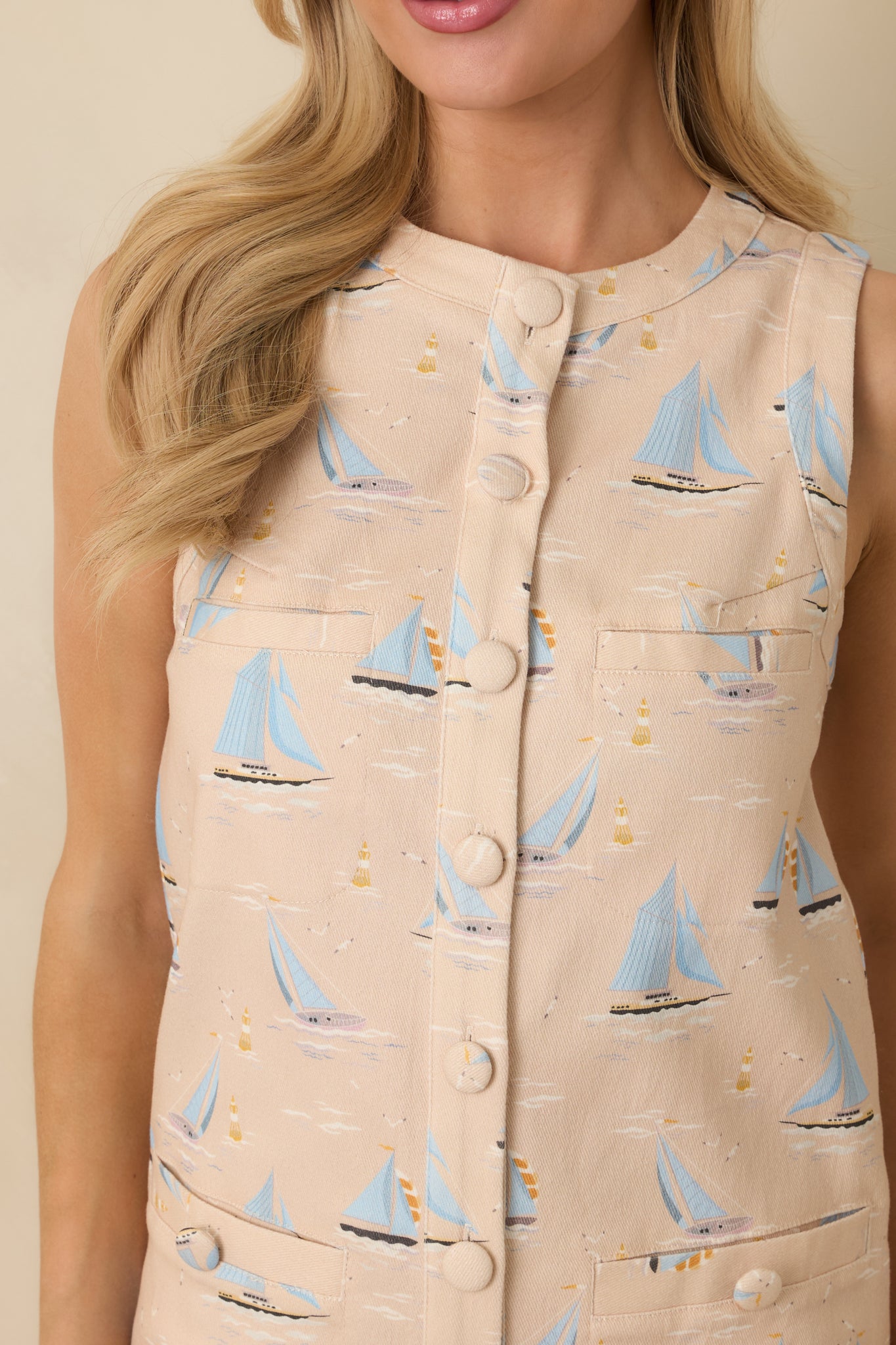 Detailed view of light beige mini dress showing the button-front closure, round neckline, and sailboat print pattern.