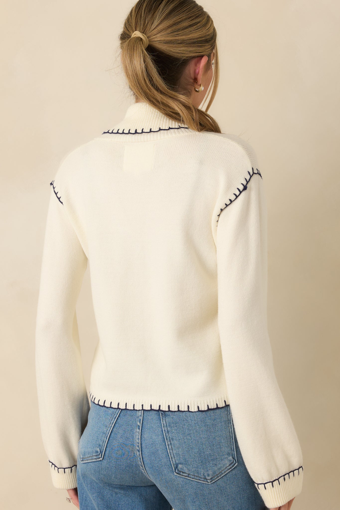 Ivory knit cardigan displaying the relaxed, slightly cropped silhouette from the rear with smooth knit fabric and contrast whipstitch accents.