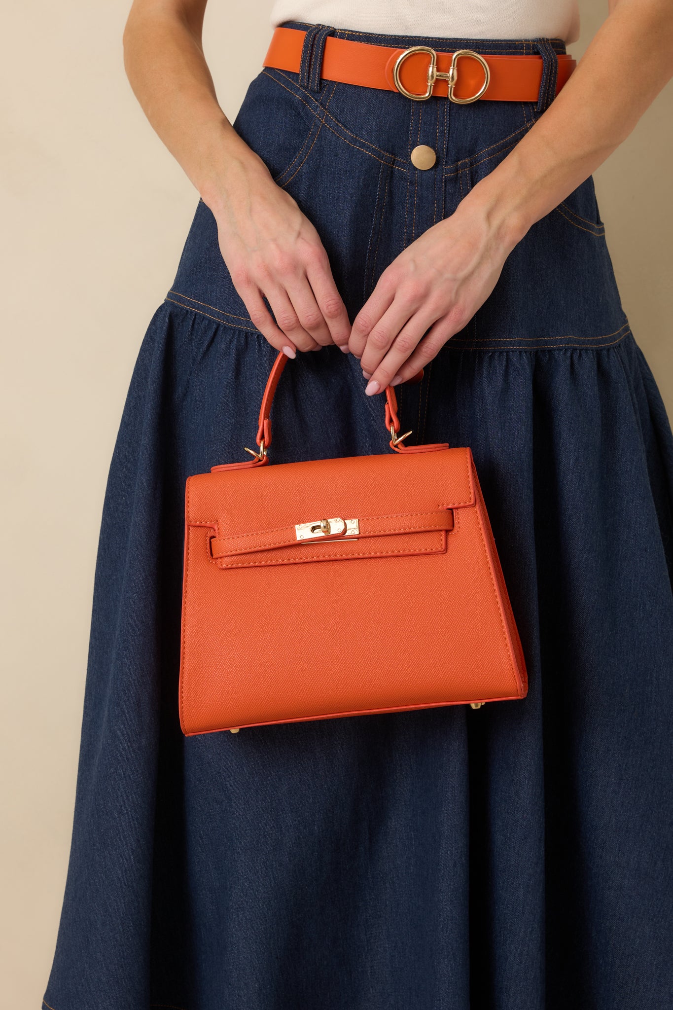 Complete image of the orange handbag highlighting the removable shoulder strap and clean, boxy silhouette.