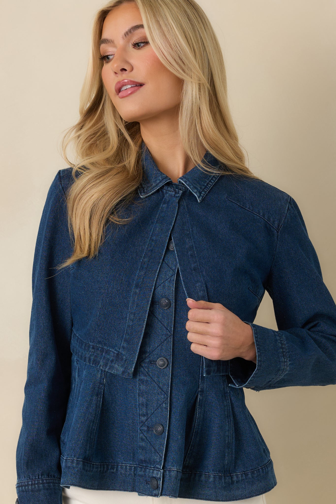 Dark wash cotton jacket emphasizing the cropped hemline and long sleeves with adjustable button cuffs.