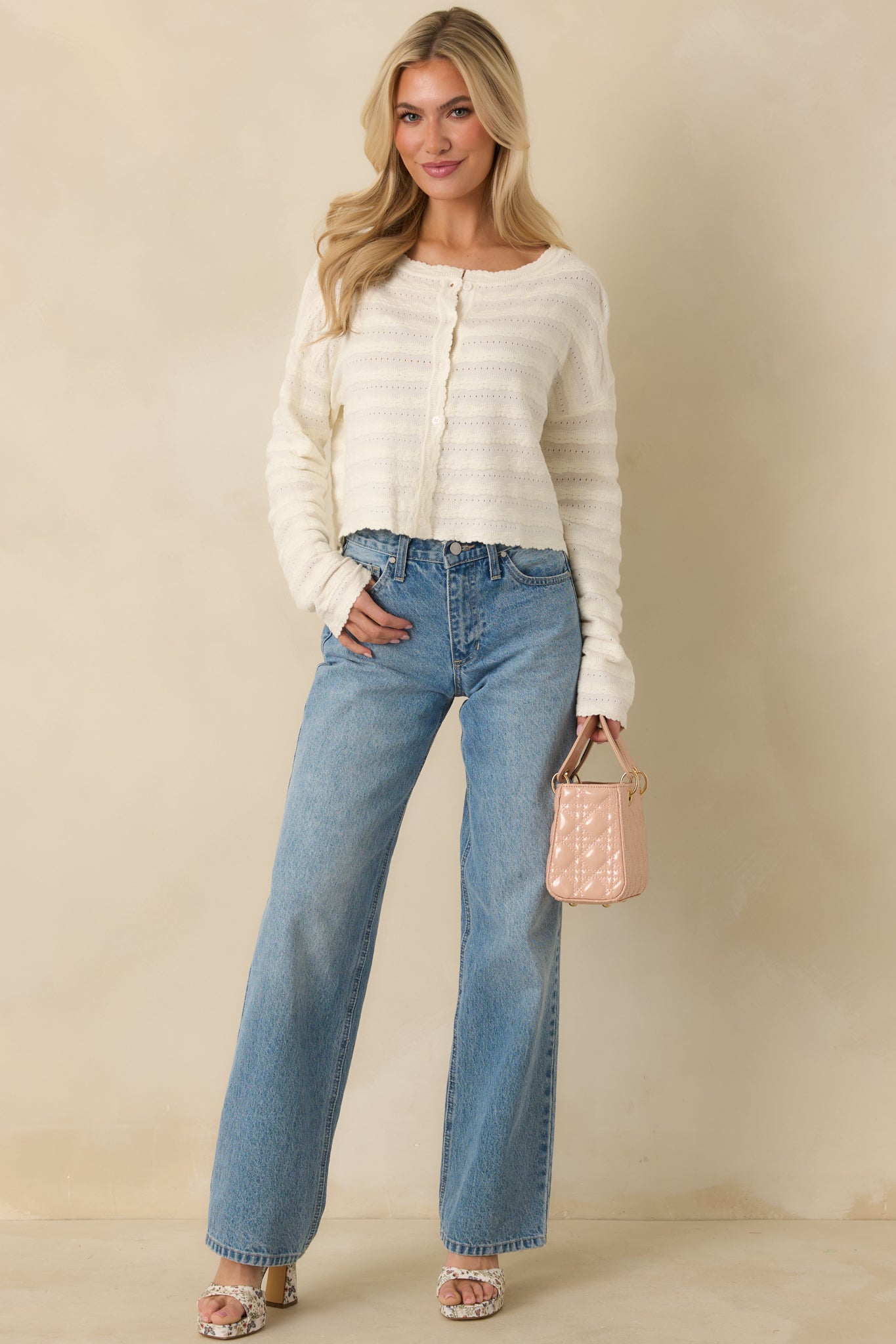 Lightweight ivory cardigan featuring a breathable textured knit, classic button-front design, and scalloped trim detailing.