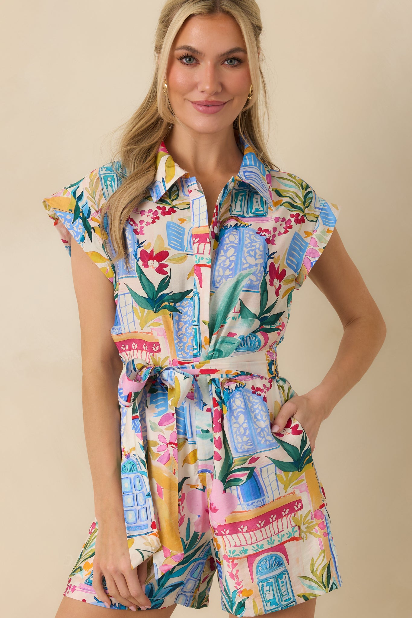 Functioning pocket detail and vibrant tropical print on lightweight blue romper.