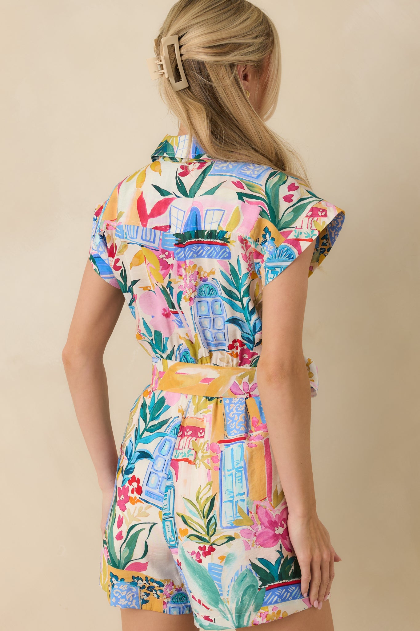 Rear view of blue print romper showing short sleeves, relaxed fit, and self-tie waistband.