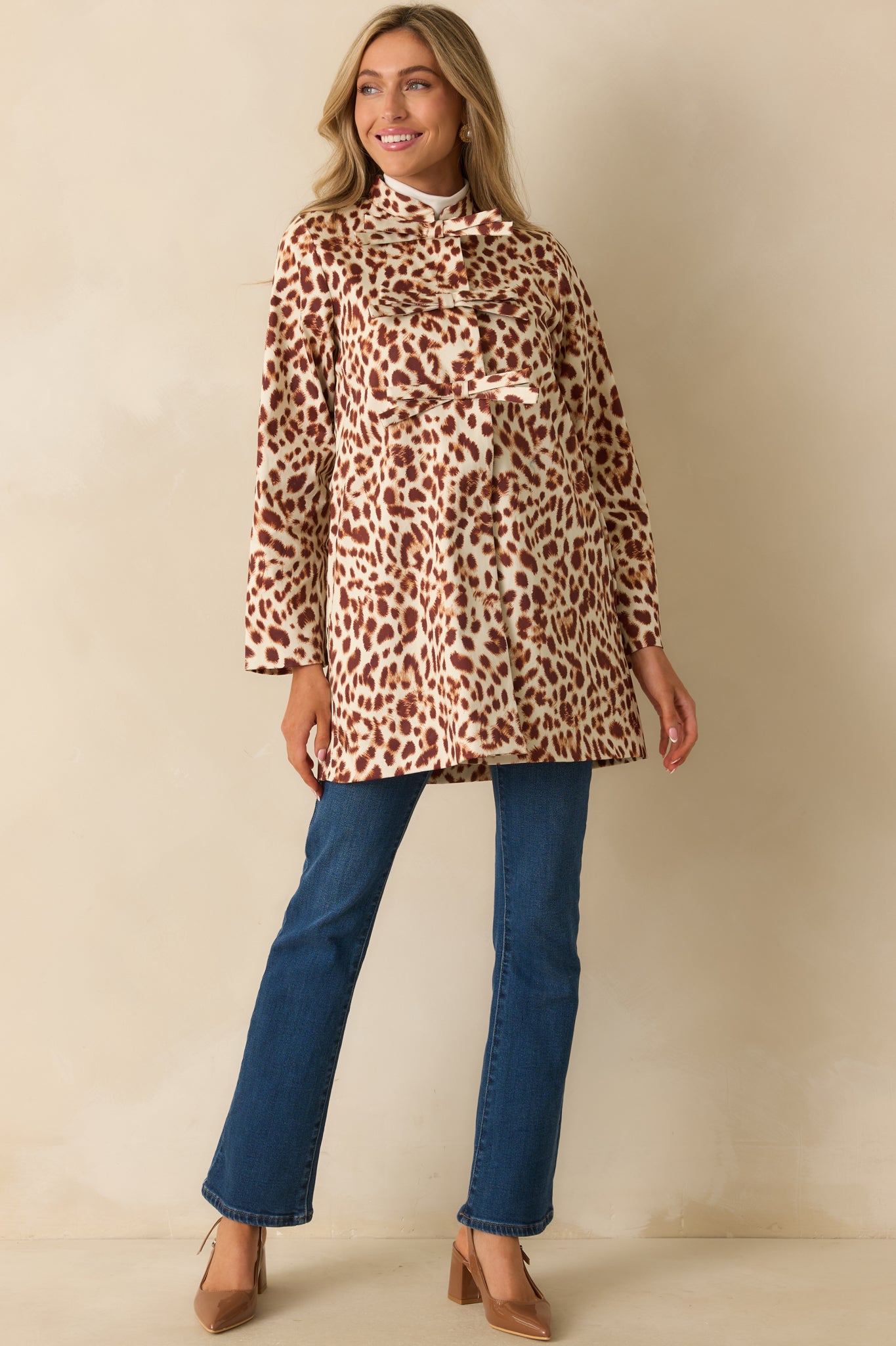 Statement leopard print coat showing its structured shape and playful bow-front detailing.