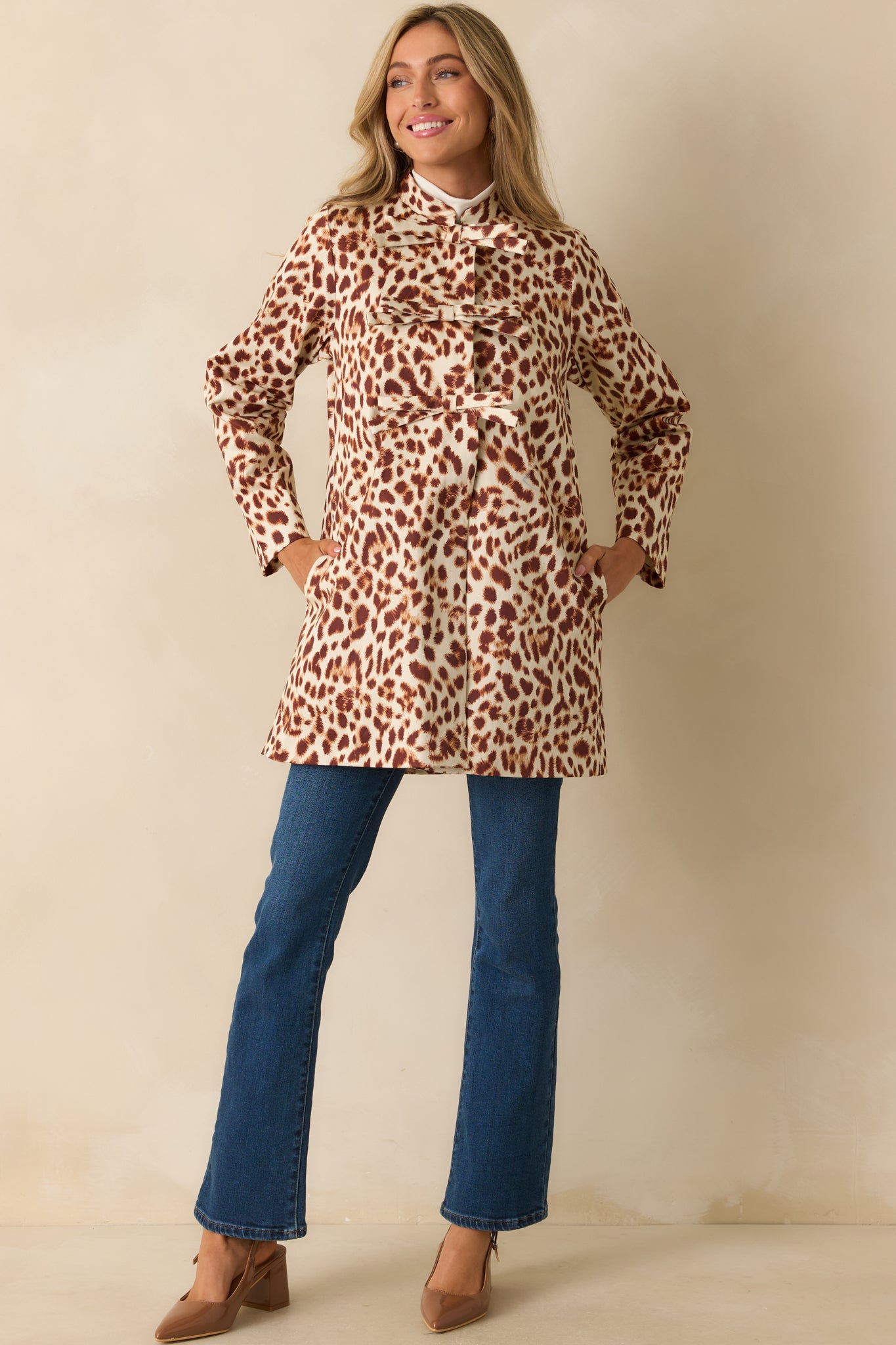 Ivory and brown abstract leopard print coat with a high collar and decorative bow front closures.