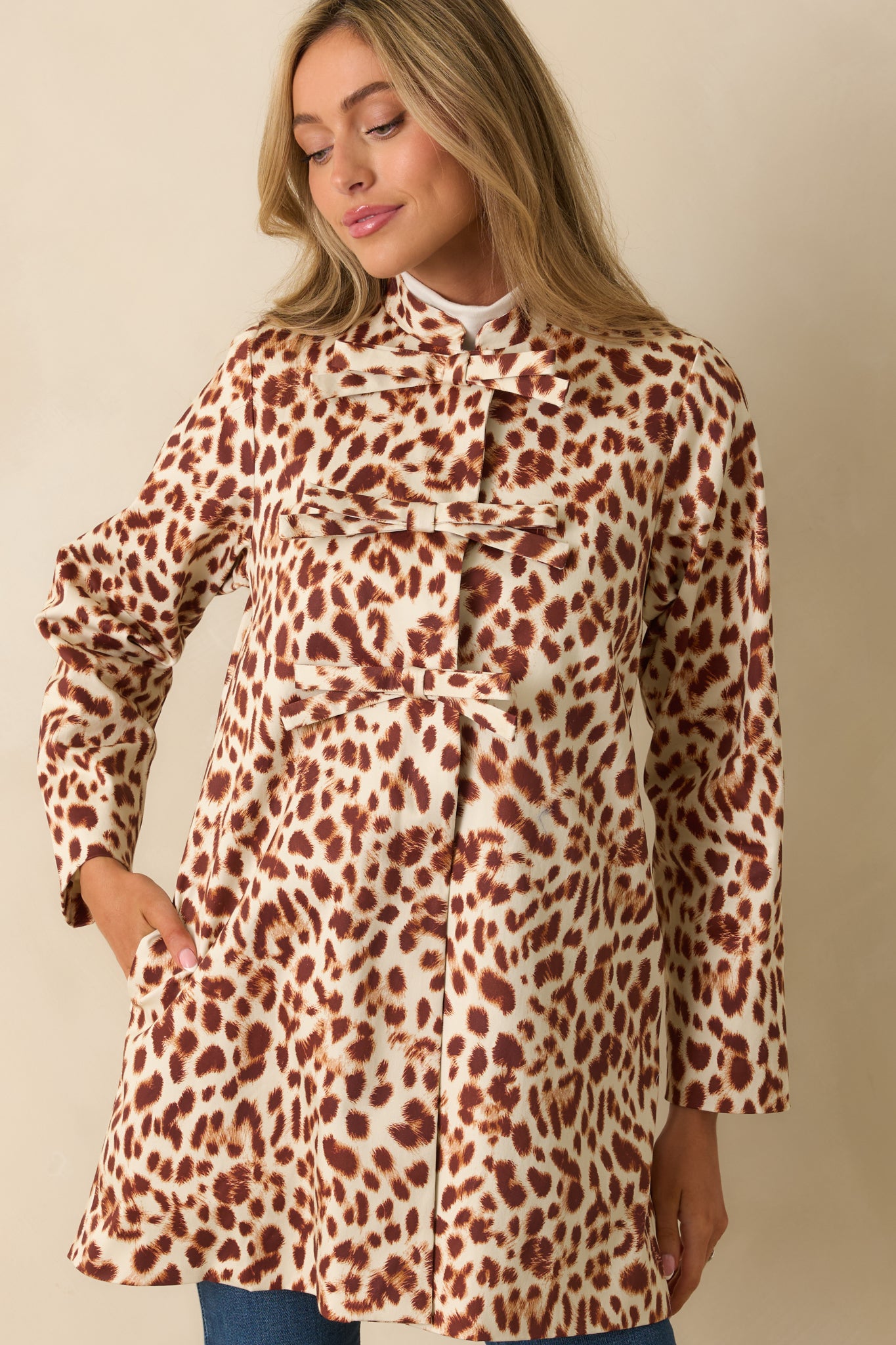 Close view of the decorative bow closures and abstract leopard print on the front of the coat.