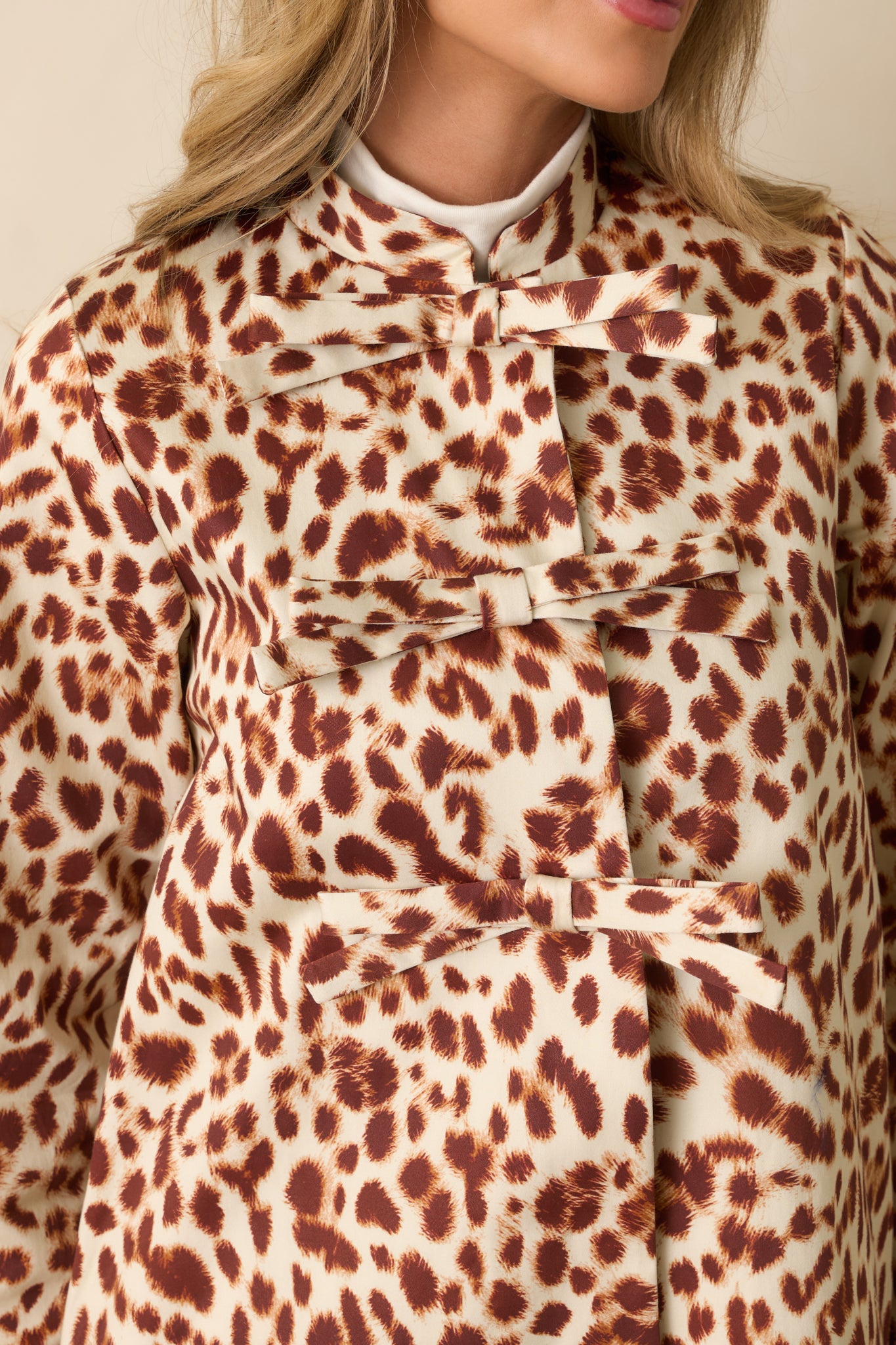 Detailed close-up of the ivory and brown leopard print fabric and bow closure hardware.