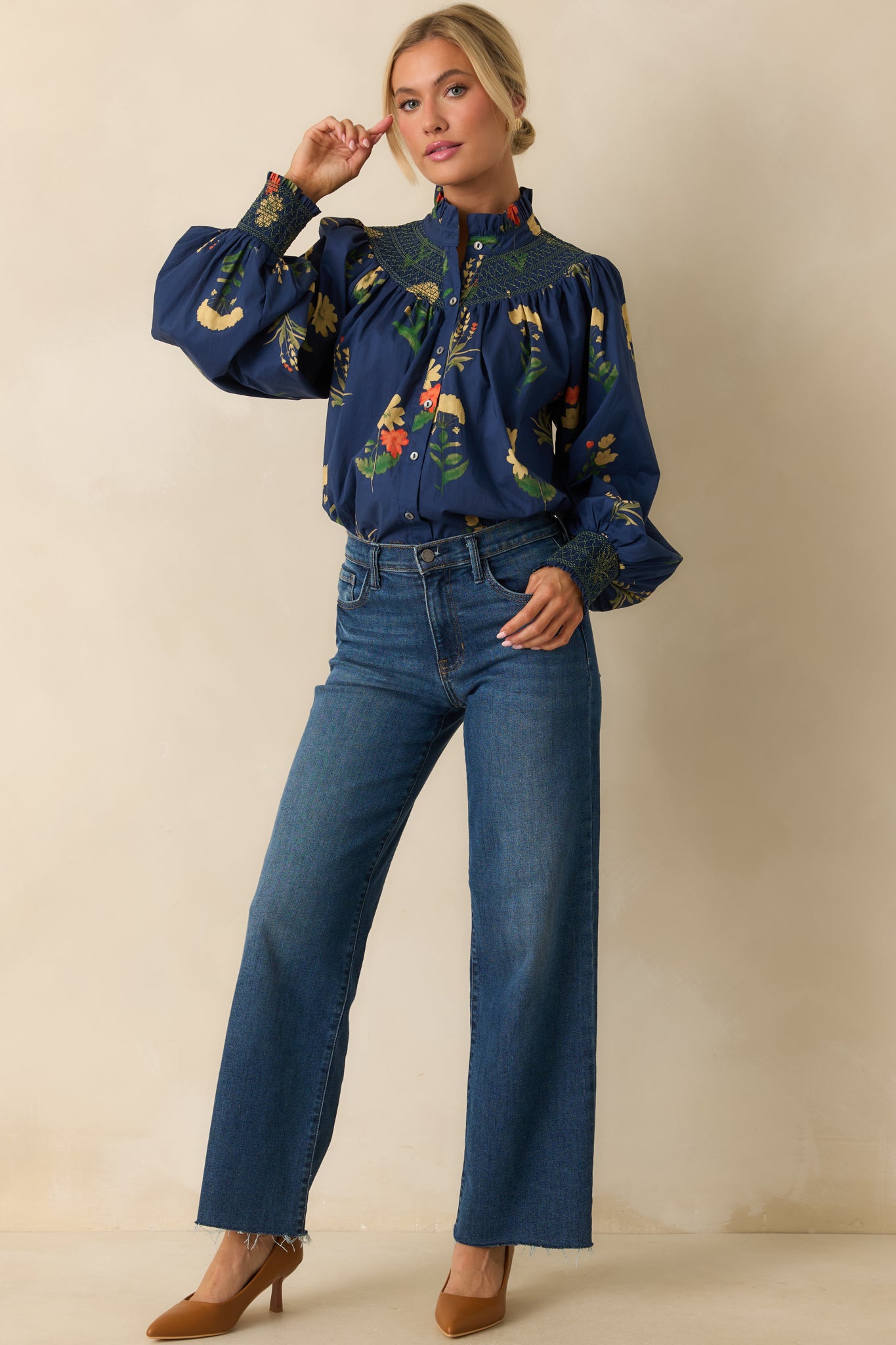Front-facing view of the navy floral blouse highlighting the ruffled stand collar, smocked yoke, and flowing silhouette.