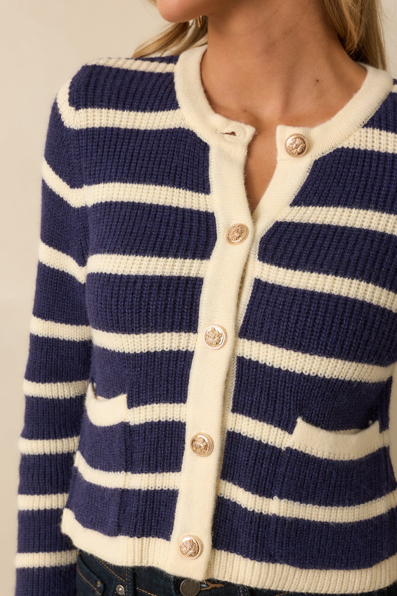 Close-up capturing the fine knit pattern, polished button finish, and subtle texture of the navy stripes.