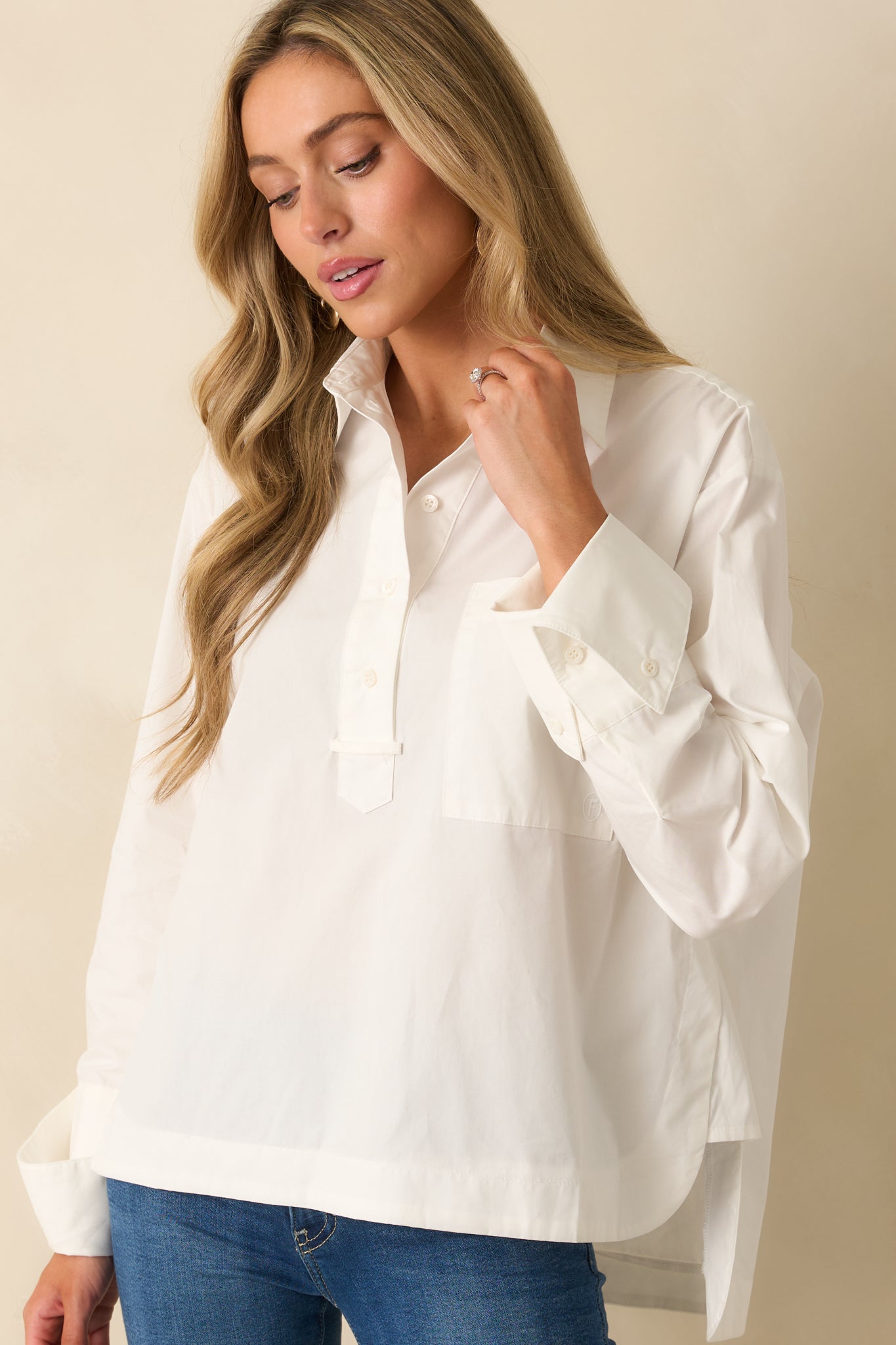 Focus on the long sleeves and buttoned cuffs of the white blouse
