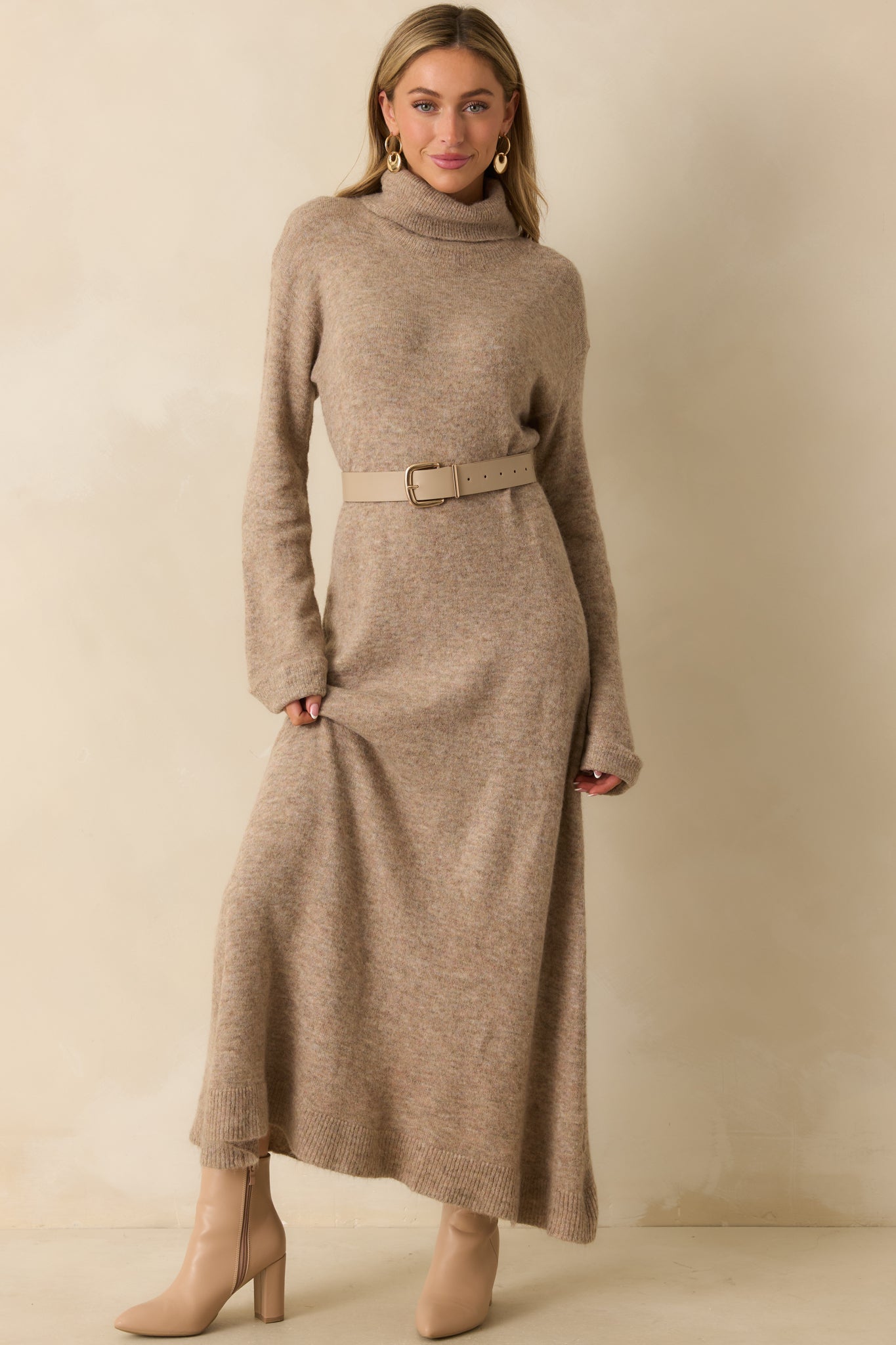 Full view of the beige knit dress emphasizing the turtleneck neckline and flowing maxi length.