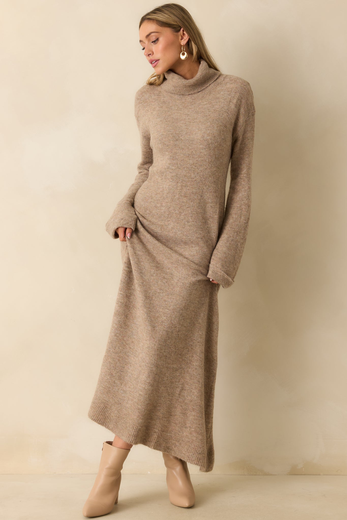 Full front view of the beige knit maxi dress showing the long sleeves and cozy, sweater-like knit drape.