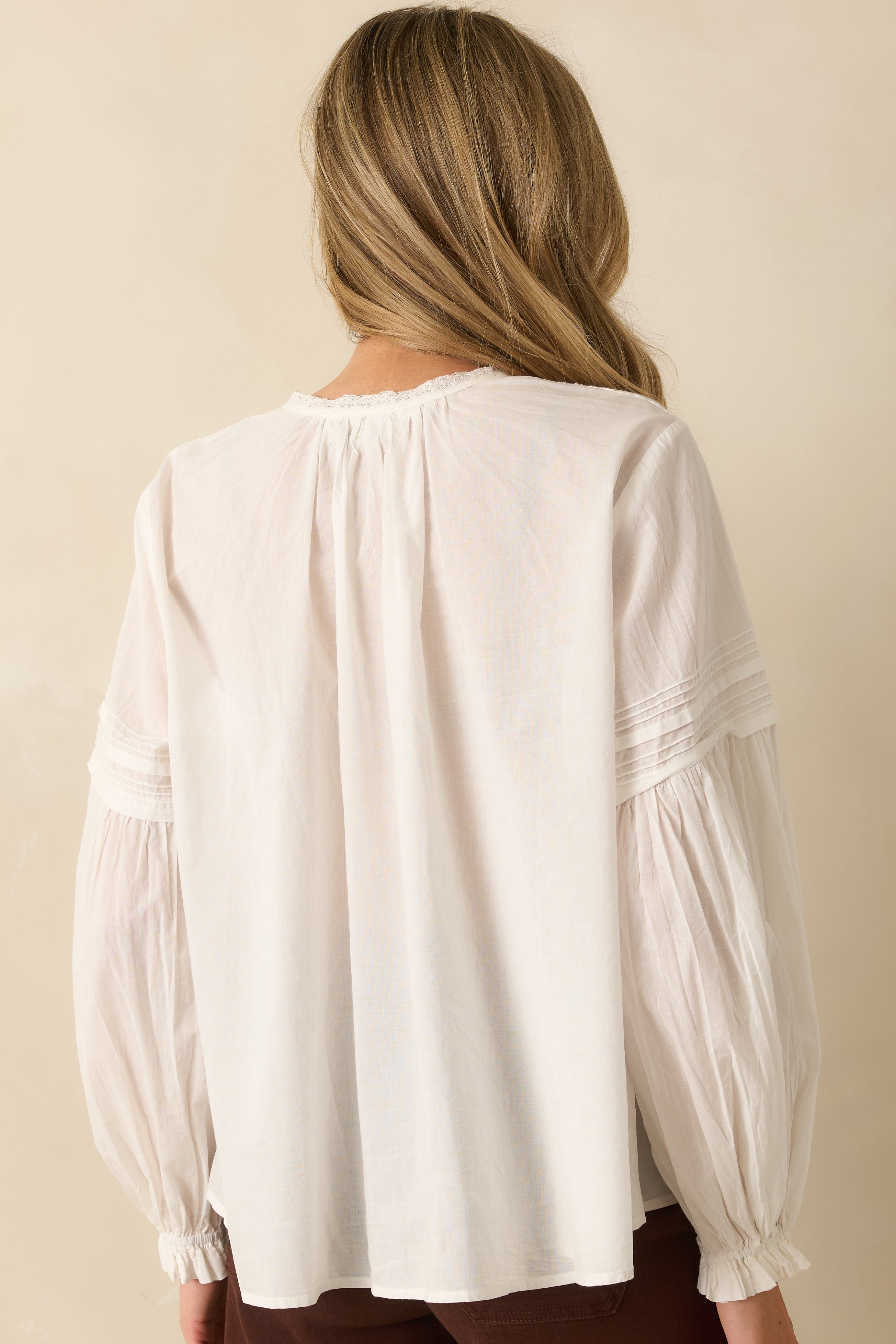 Rear view of the white cotton blouse showing long peasant sleeves and relaxed silhouette.