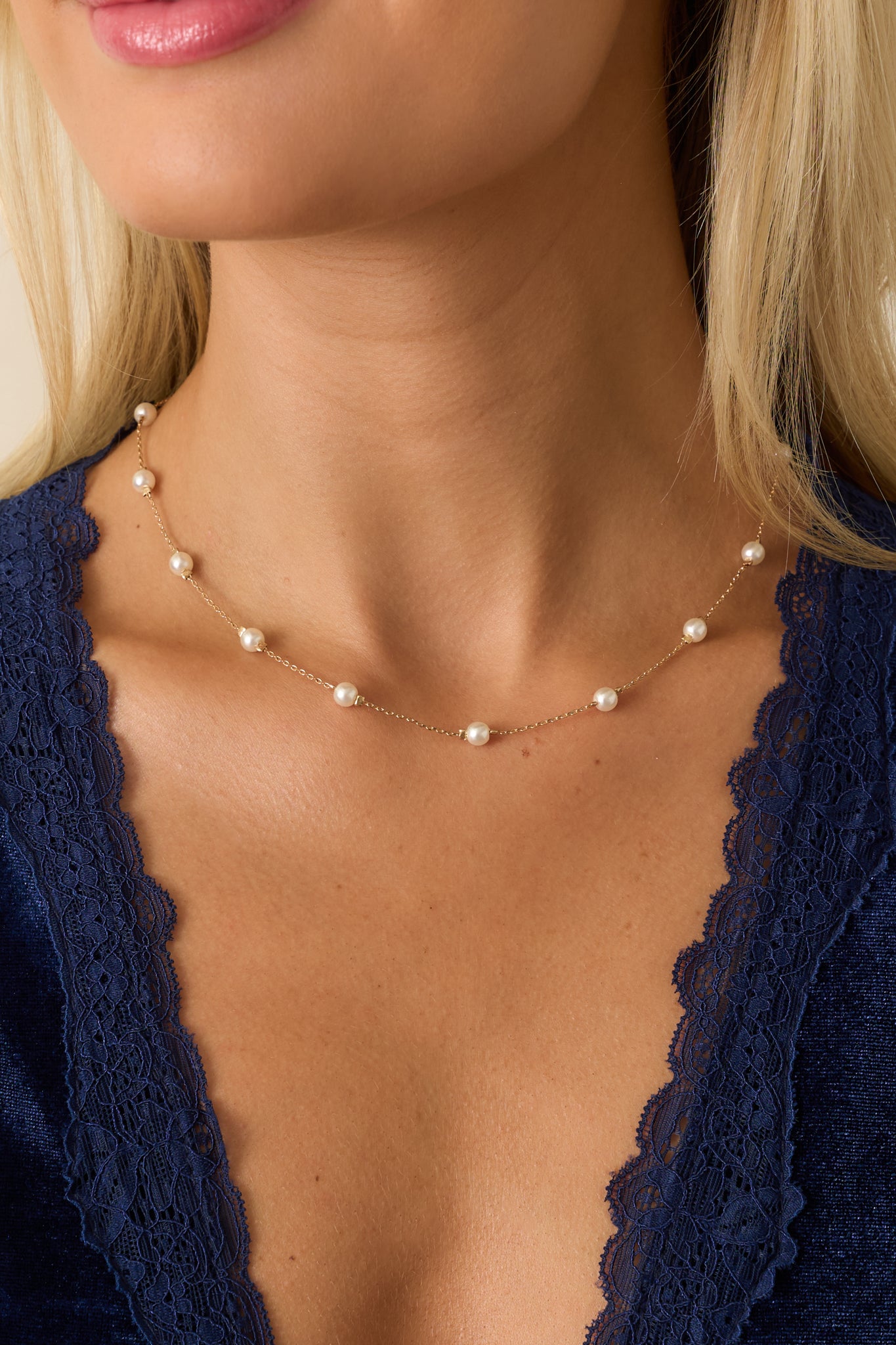 Gold-toned chain necklace with small evenly spaced faux pearls and lobster clasp closure.