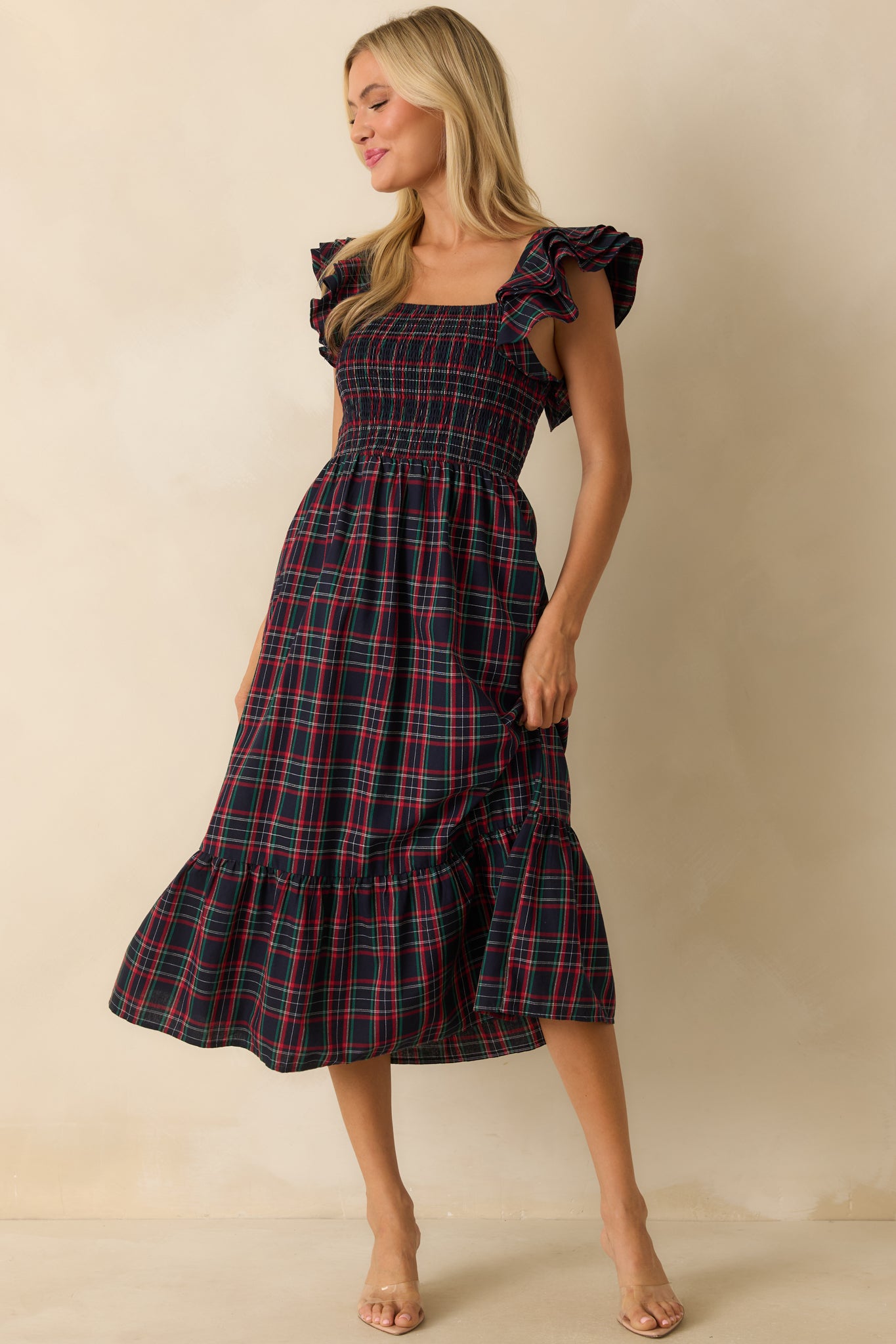 Slim-fit smocked navy dress with flutter sleeves, square neckline, and tiered plaid skirt