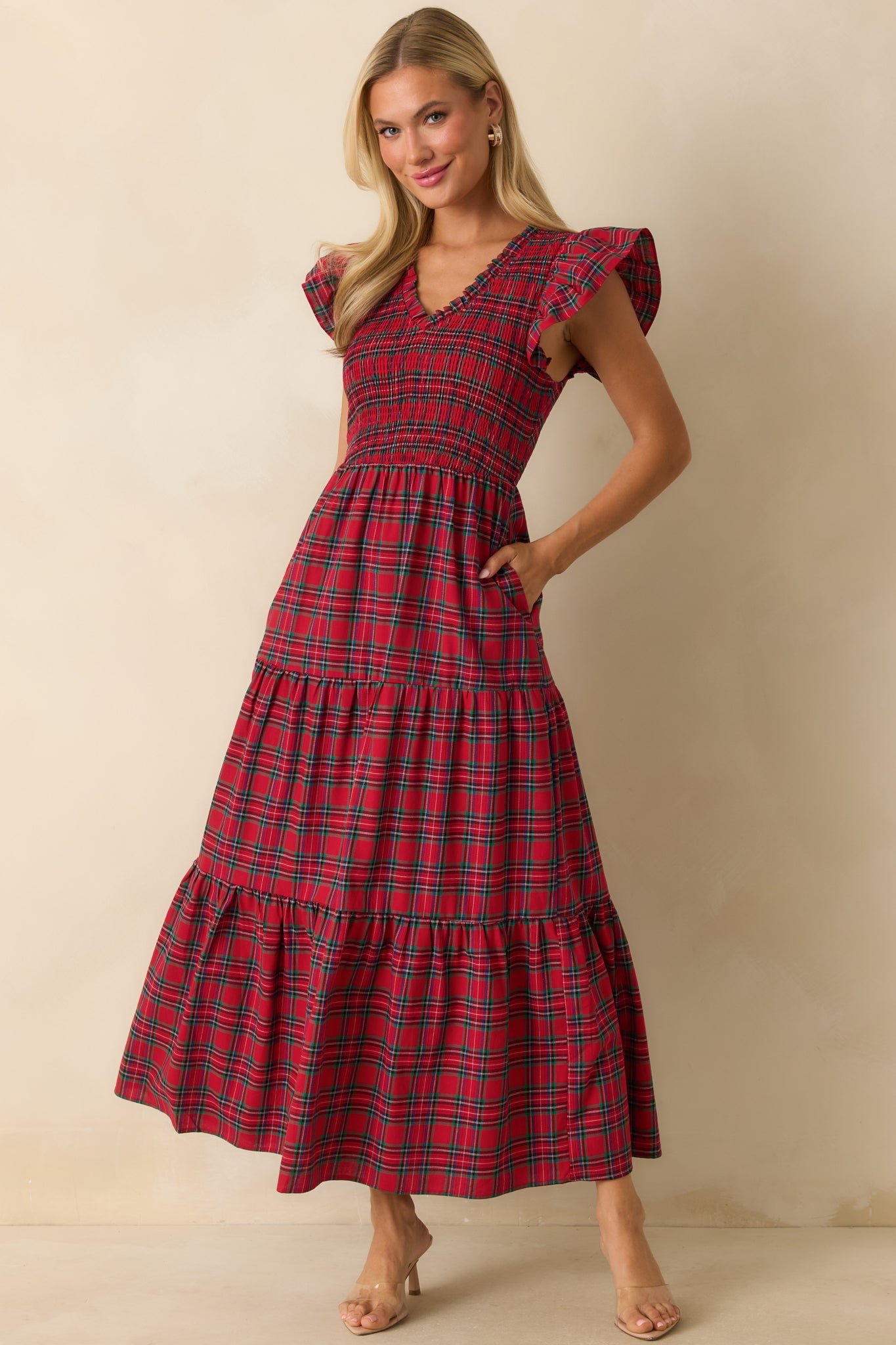 Red plaid maxi dress with a v-neckline, smocked bodice, flutter sleeves, and tiered skirt.