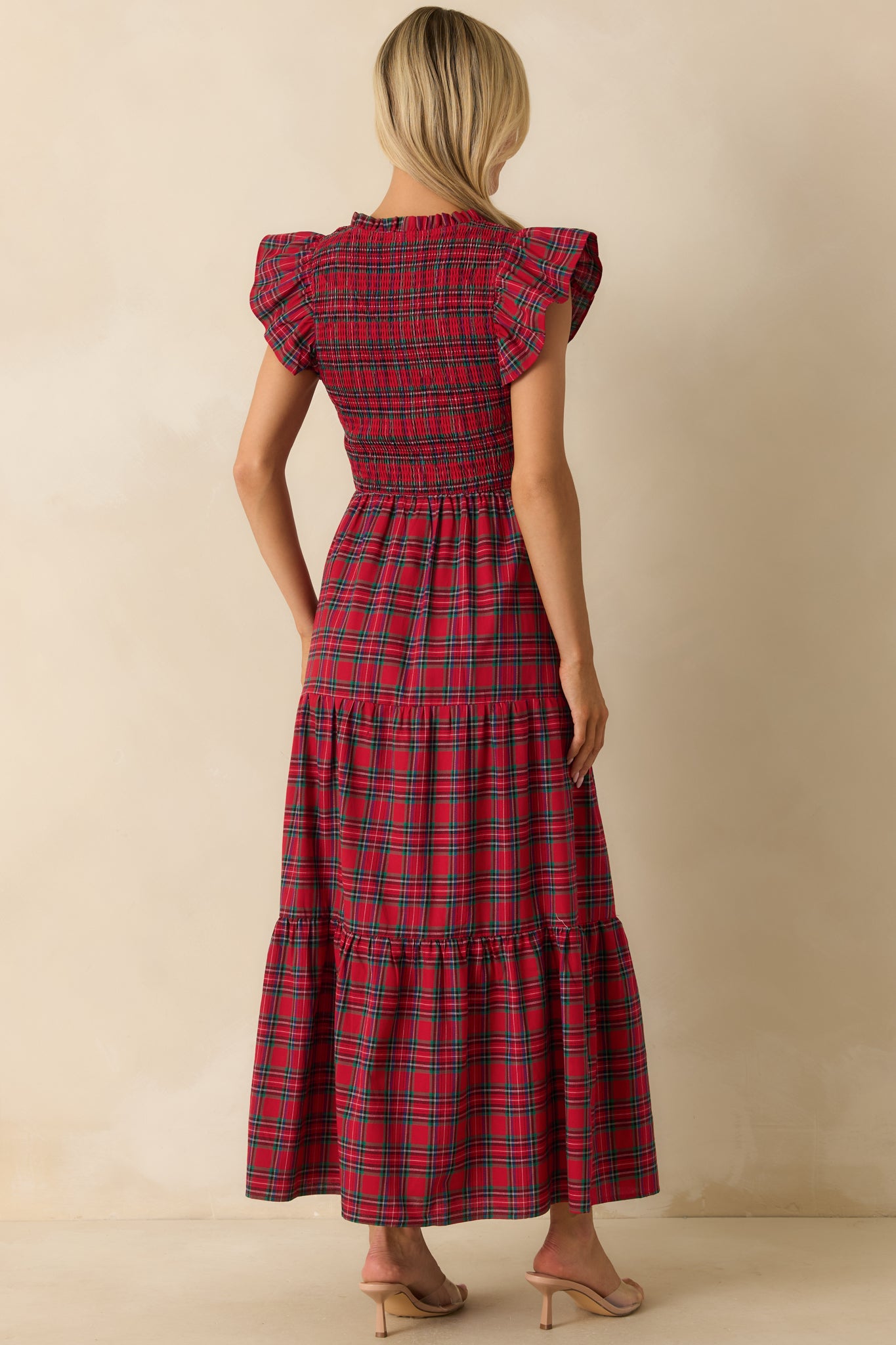 Rear view of red plaid maxi dress showing smocked back, flutter sleeves, and layered tiered skirt.