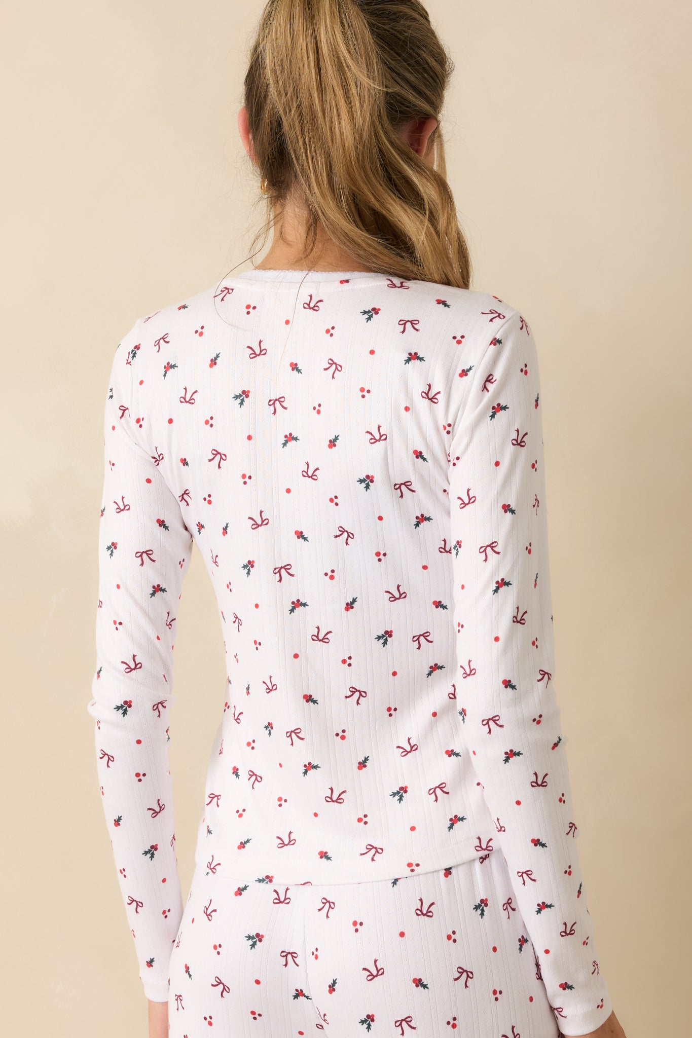Rear view of white long-sleeve henley, highlighting fitted silhouette, smooth Pointelle knit, and allover holiday print.