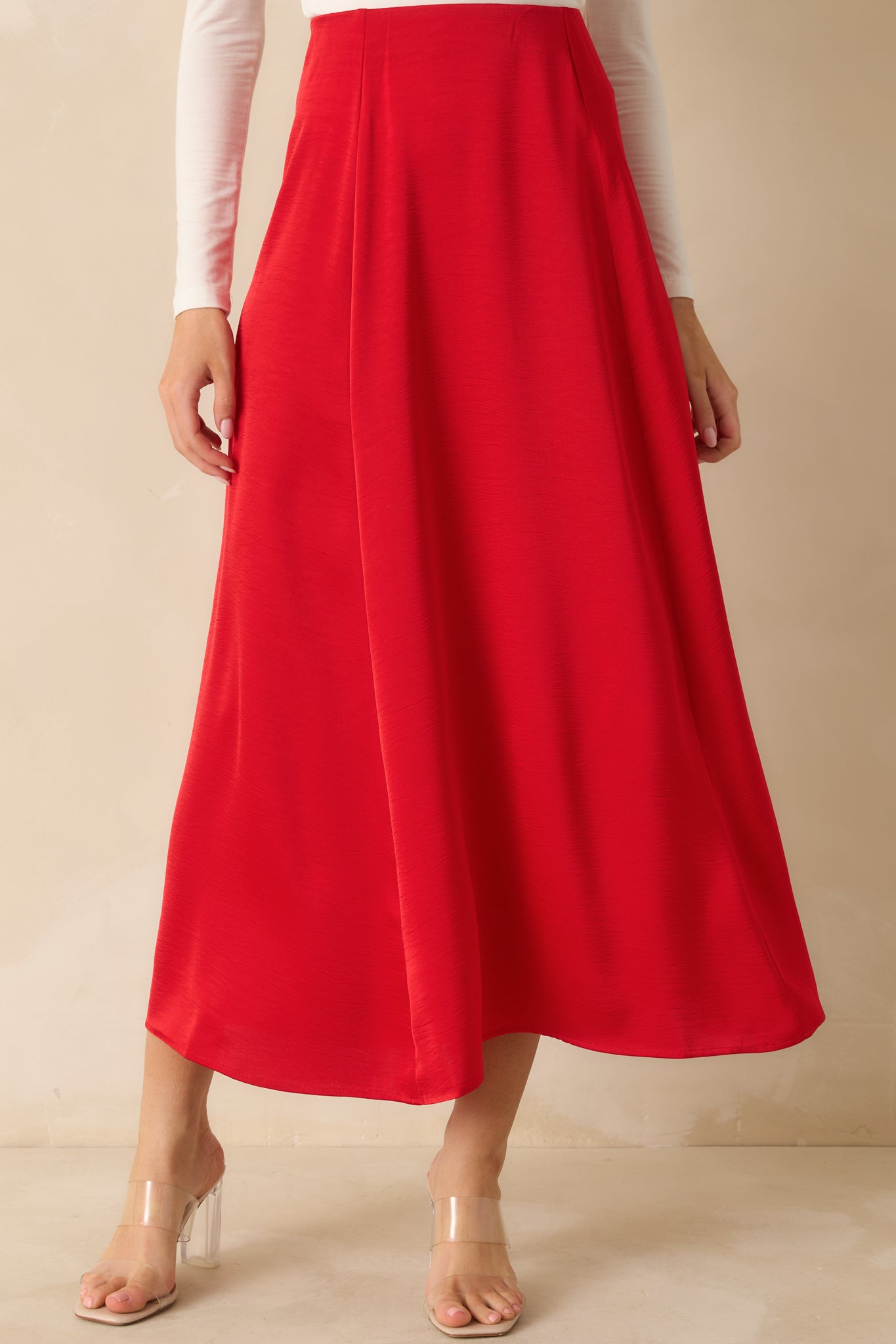 Red A-line satin skirt cropped mid-leg, emphasizing fluid drape and high-rise fit.