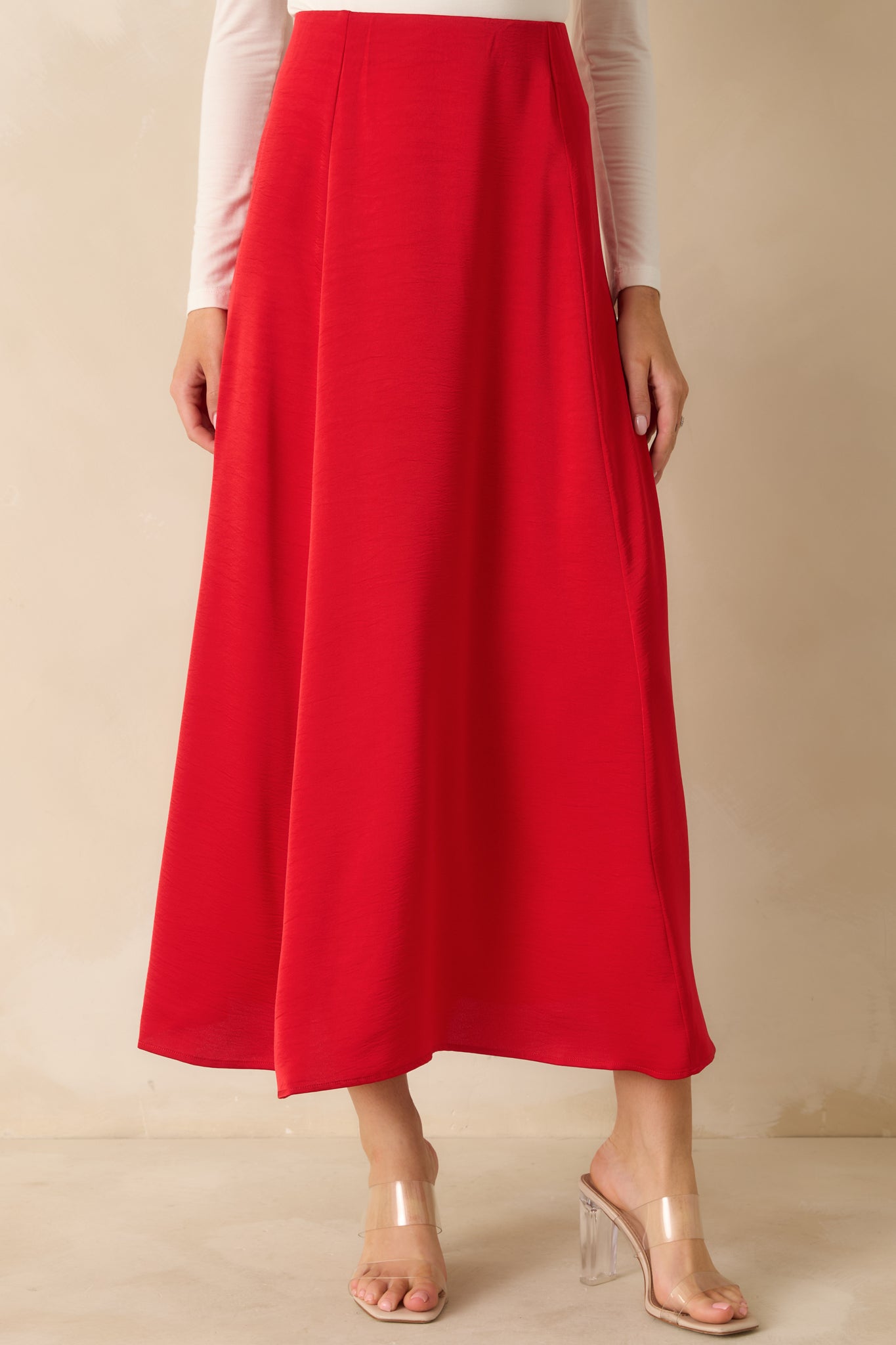 Detail of the front of red midi skirt, showing silky satin fabric and smooth waistband finish.